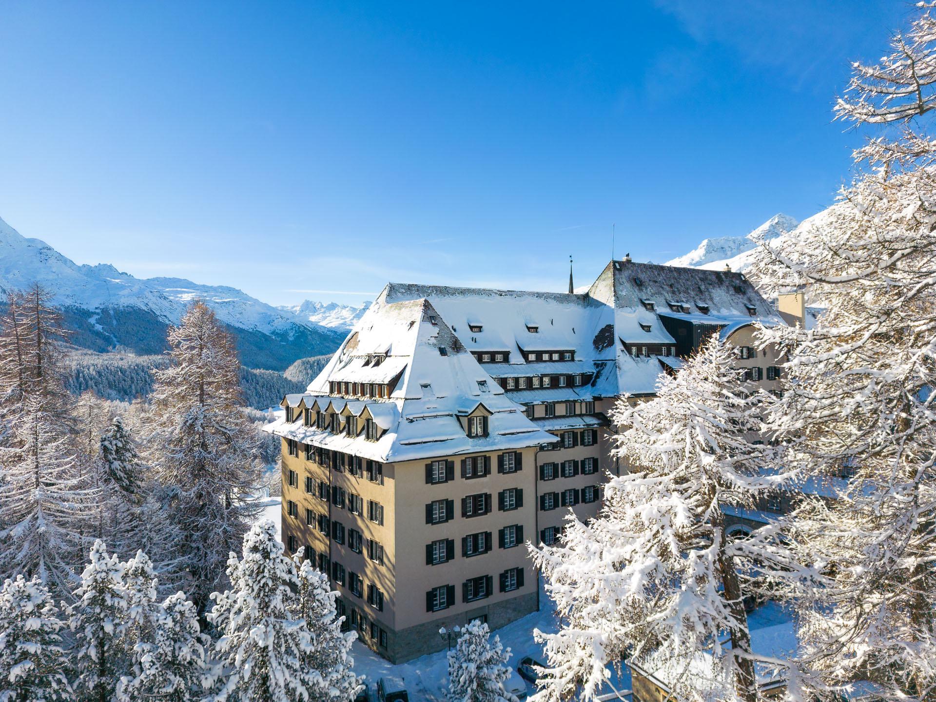 Suvretta House: a white Belle Époque hotel on a forested mountain plateau with snow-capped peaks