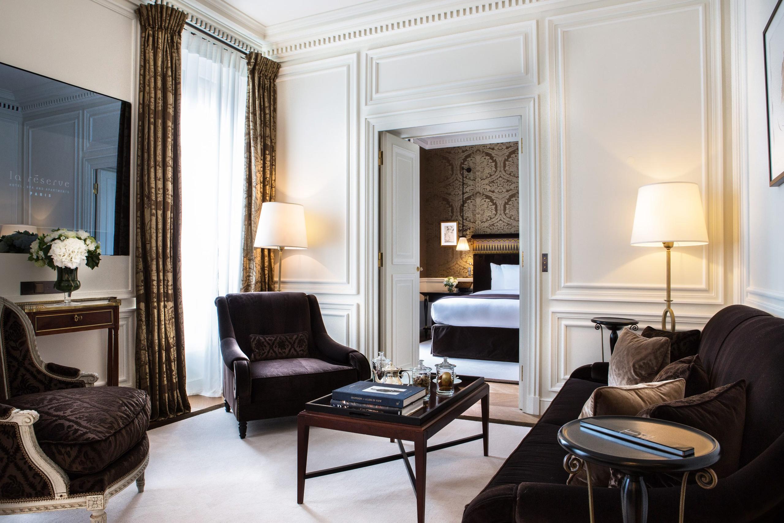 A suite with black velvet armchairs, warm wood furnishings, and layered lighting