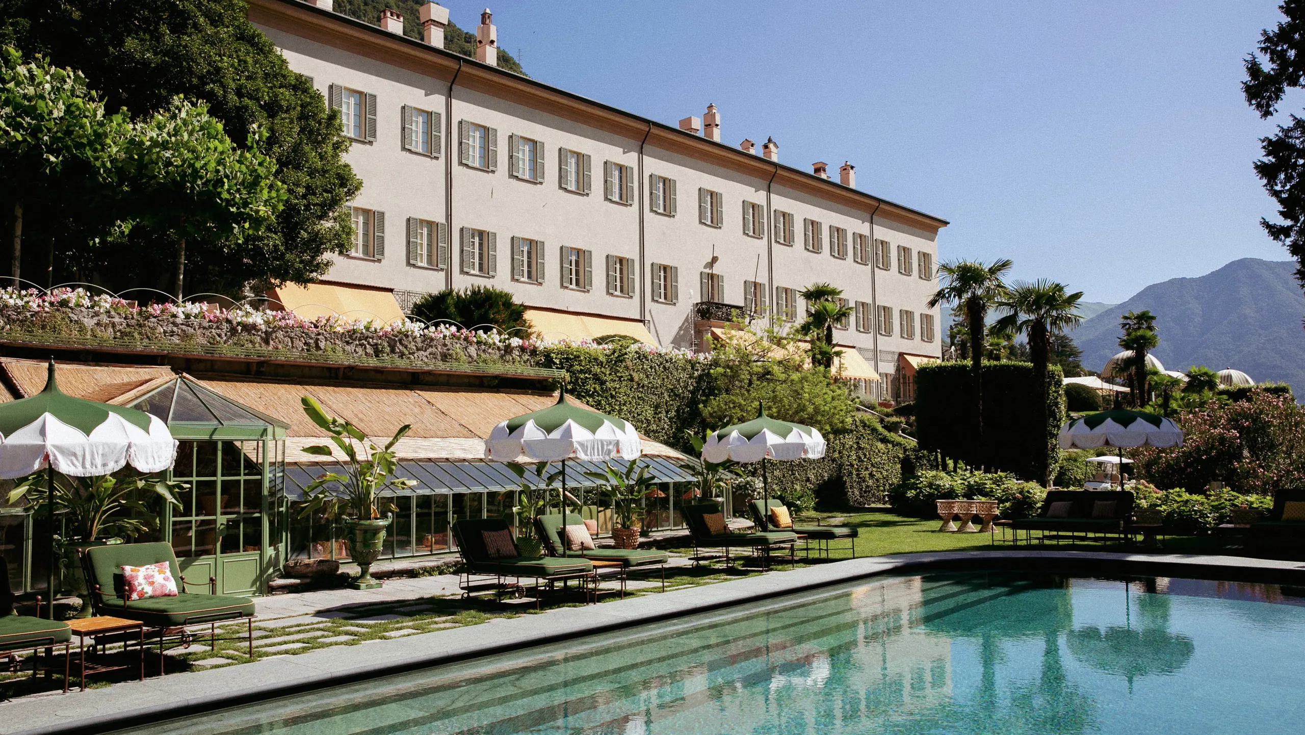 Passalacqua: a palazzo facade with manicured grounds, pool terrace, and white umbrellas