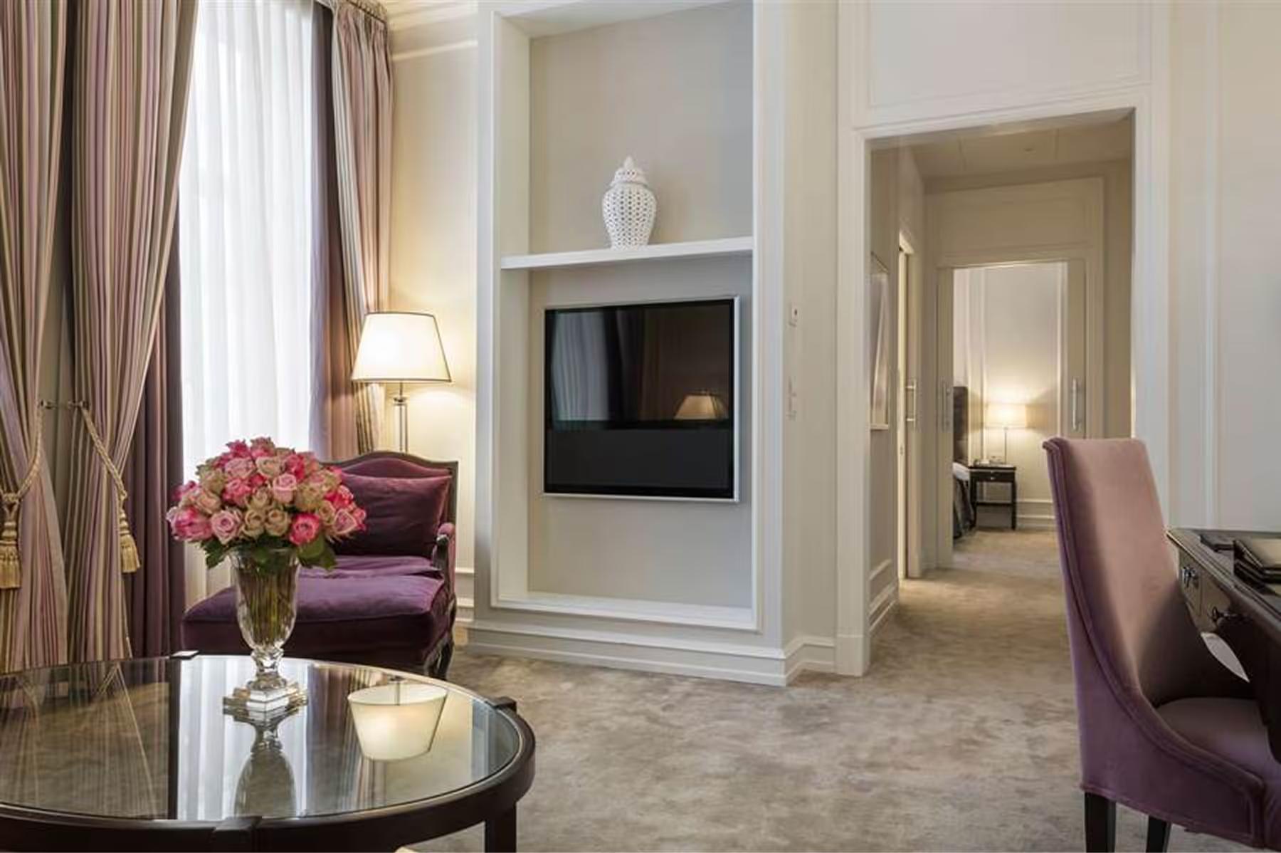 Hotel d’Angleterre: suite sitting area with fireplace, burgundy chair, and cream furnishings