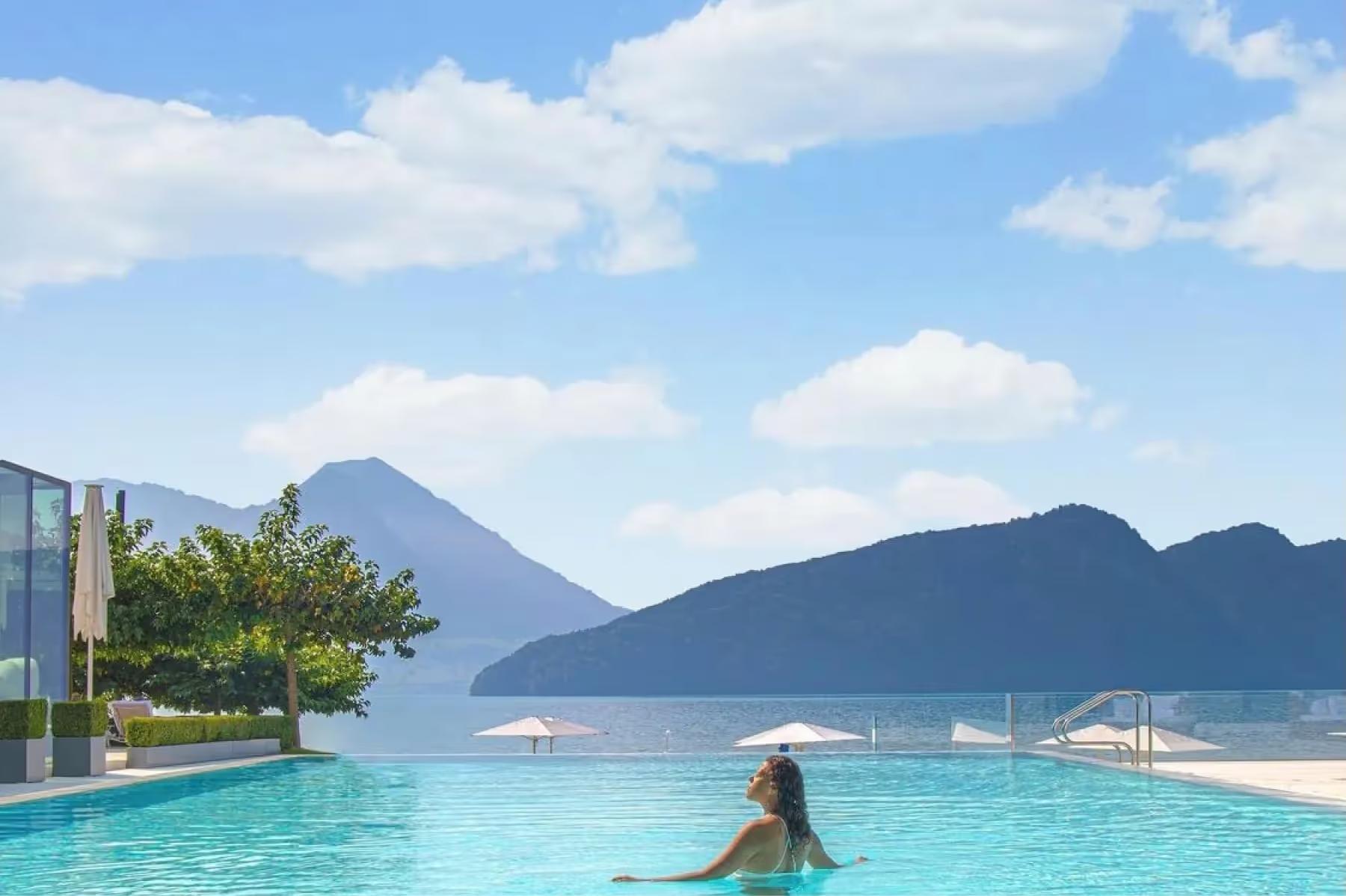Park Hotel Vitznau: infinity pool overlooking Alpine peaks and distant lake under blue sky