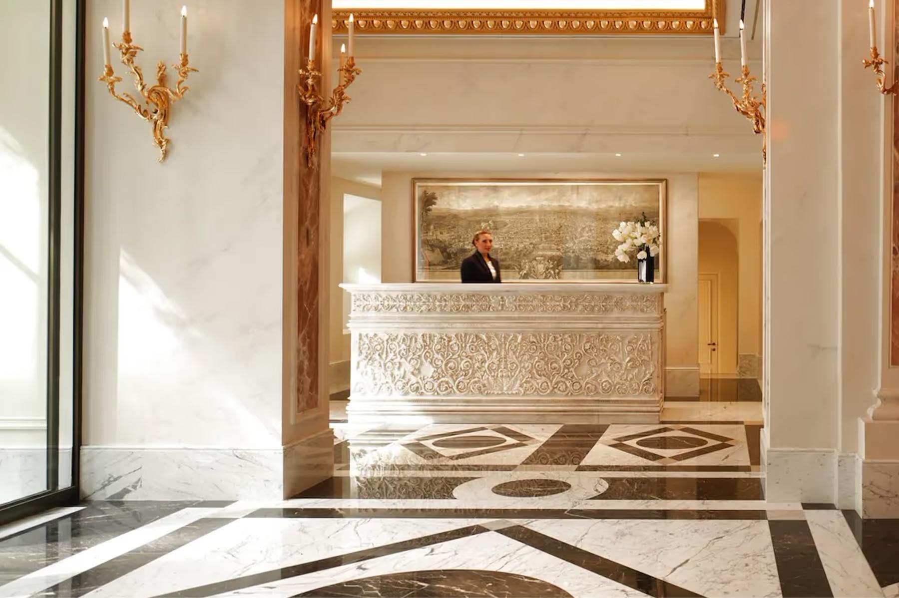 Hotel Eden: the hotel lobby with an ornate ceiling, arched doorway to the reception desk, and terrazzo floor in gold tones
