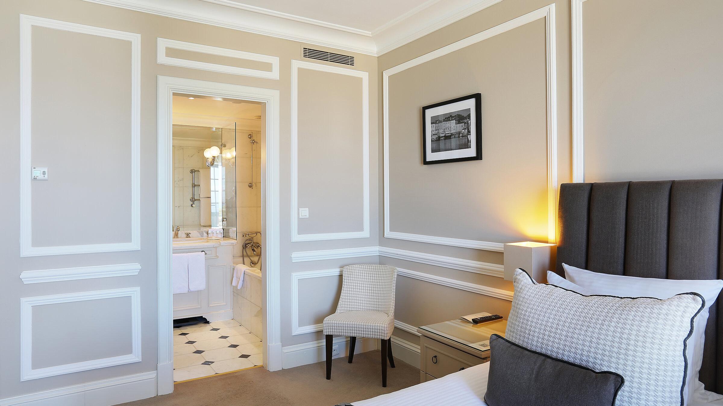 Bedroom entry with white paneling and night-lit lamps beside bed
