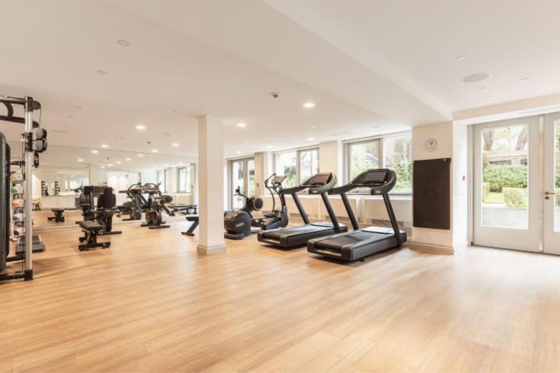 Waldorf Astoria Amsterdam: a fitness center with treadmills and exercise equipment on light wood flooring with bright natural light