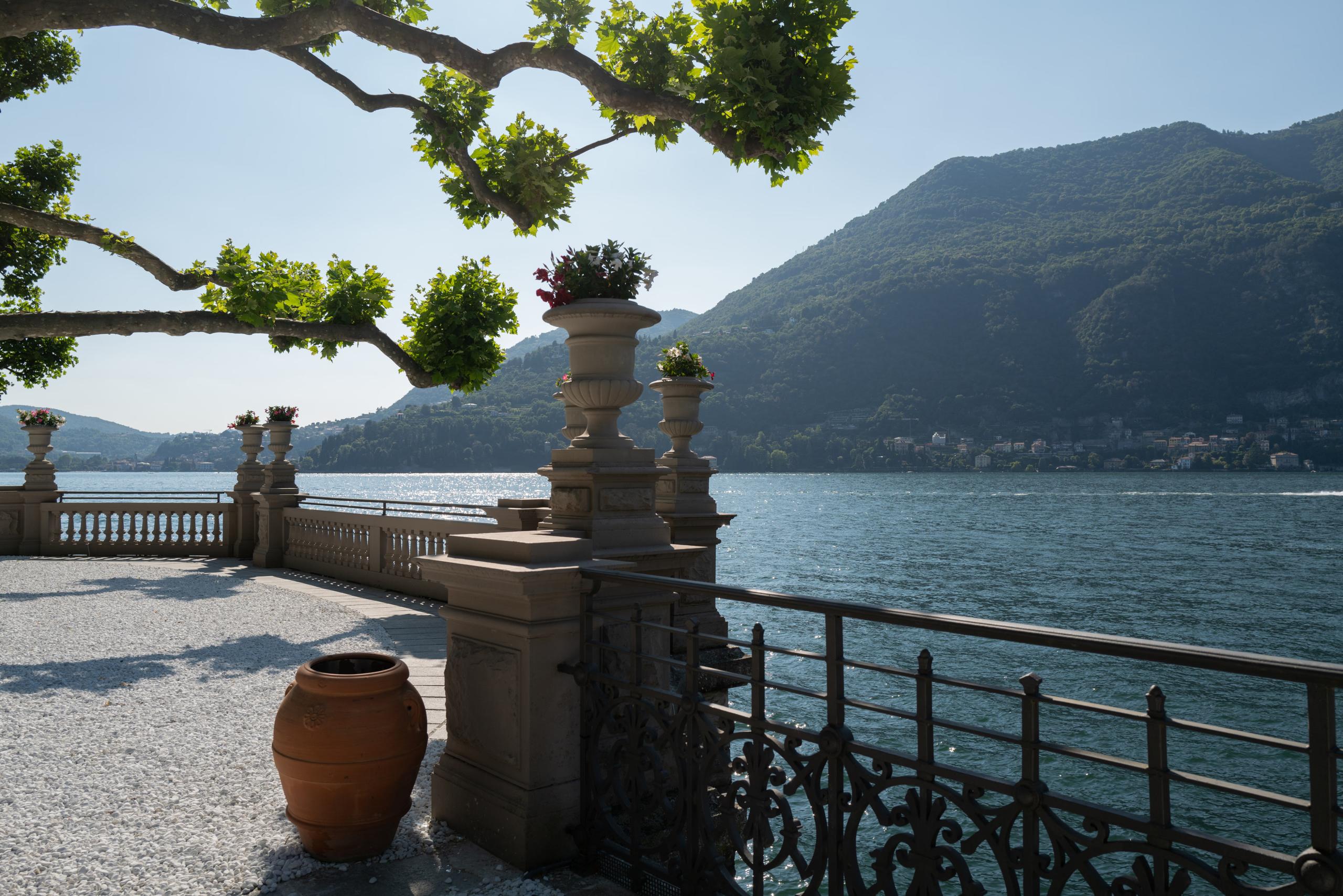 Mandarin Oriental, Lake Como: Lake vantage point framed by branches with stone balustrade, distant villages, and peaks