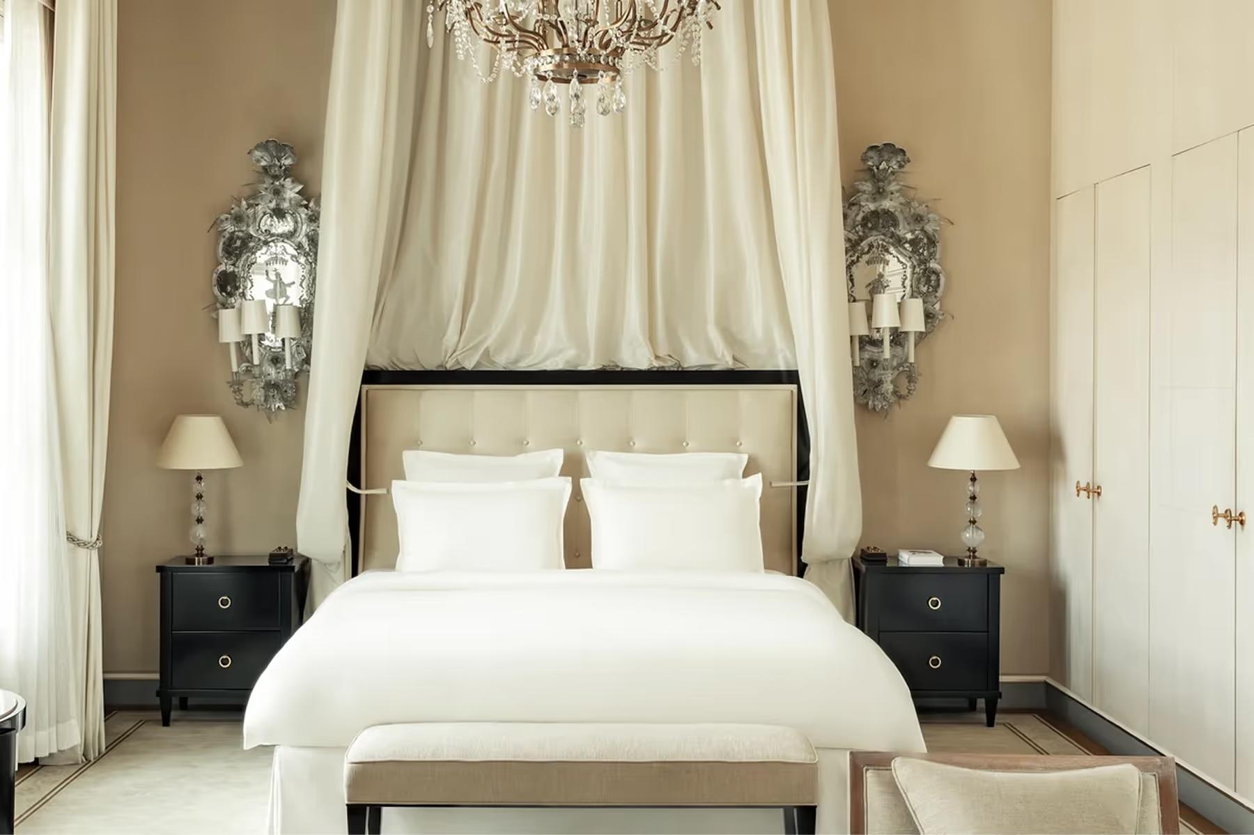Ritz Paris: a bedroom with sheer curtains, cove ceiling details, crystal chandelier, and black platform bed