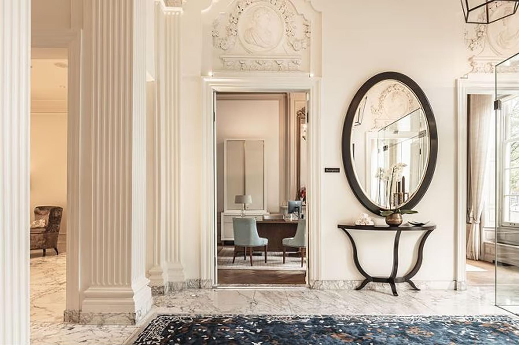 Waldorf Astoria Amsterdam: an entryway with fluted columns, arched mirrors, and a sculptural console table on marble flooring