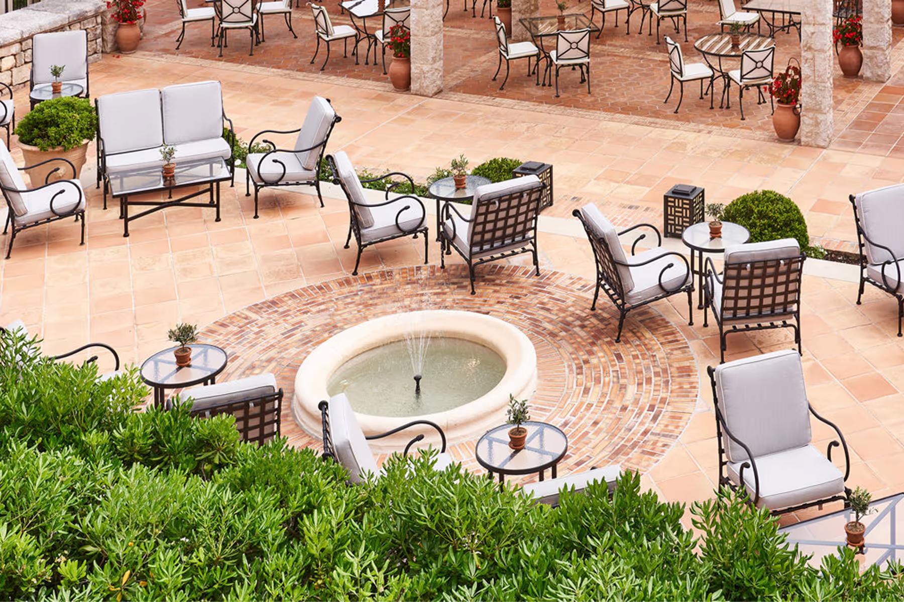 Château Saint Martin & Spa: outdoor terrace with circular fountain and tables under pergola shade