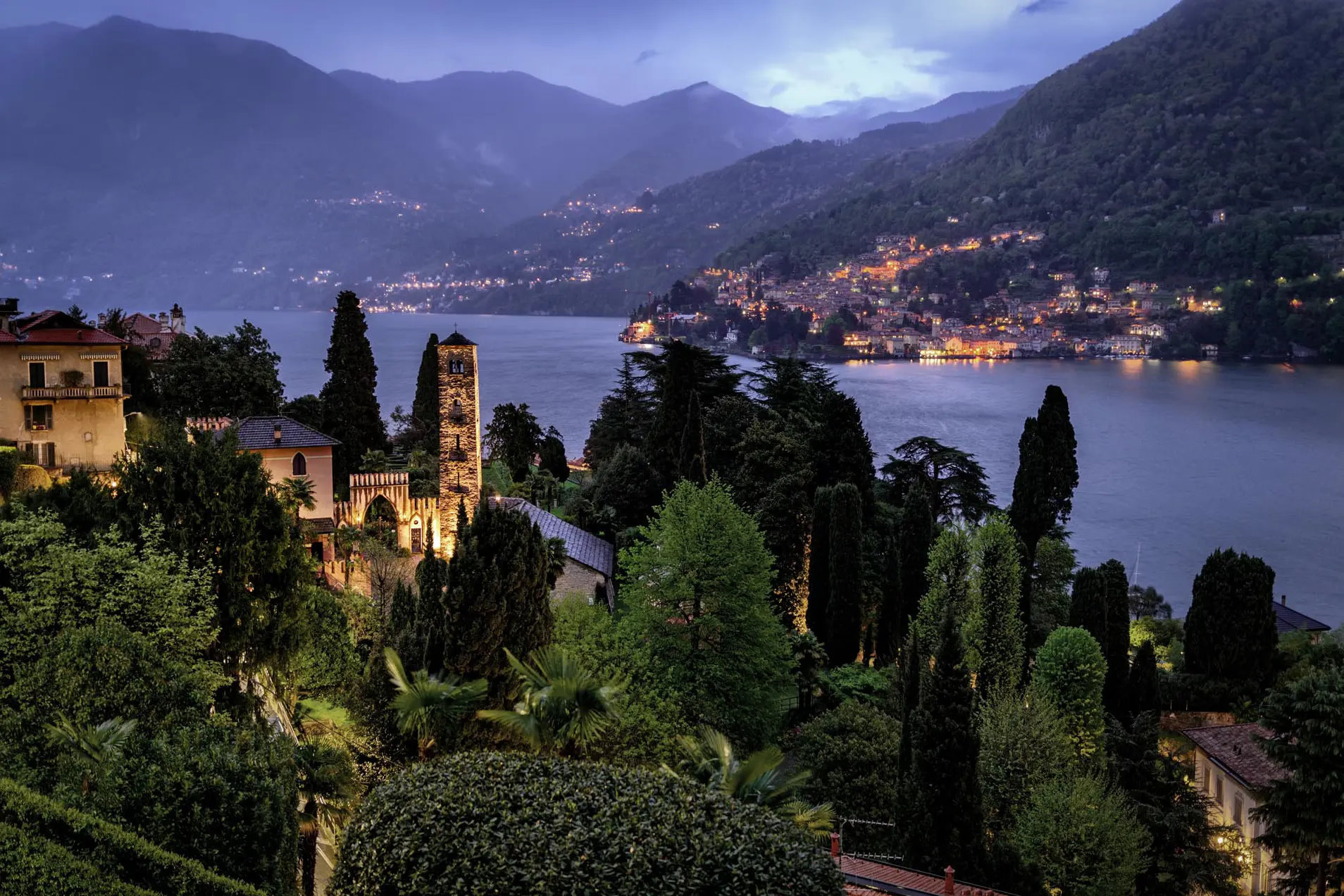 Passalacqua: twilight view of lit palazzo and cypress with lake and town lights below