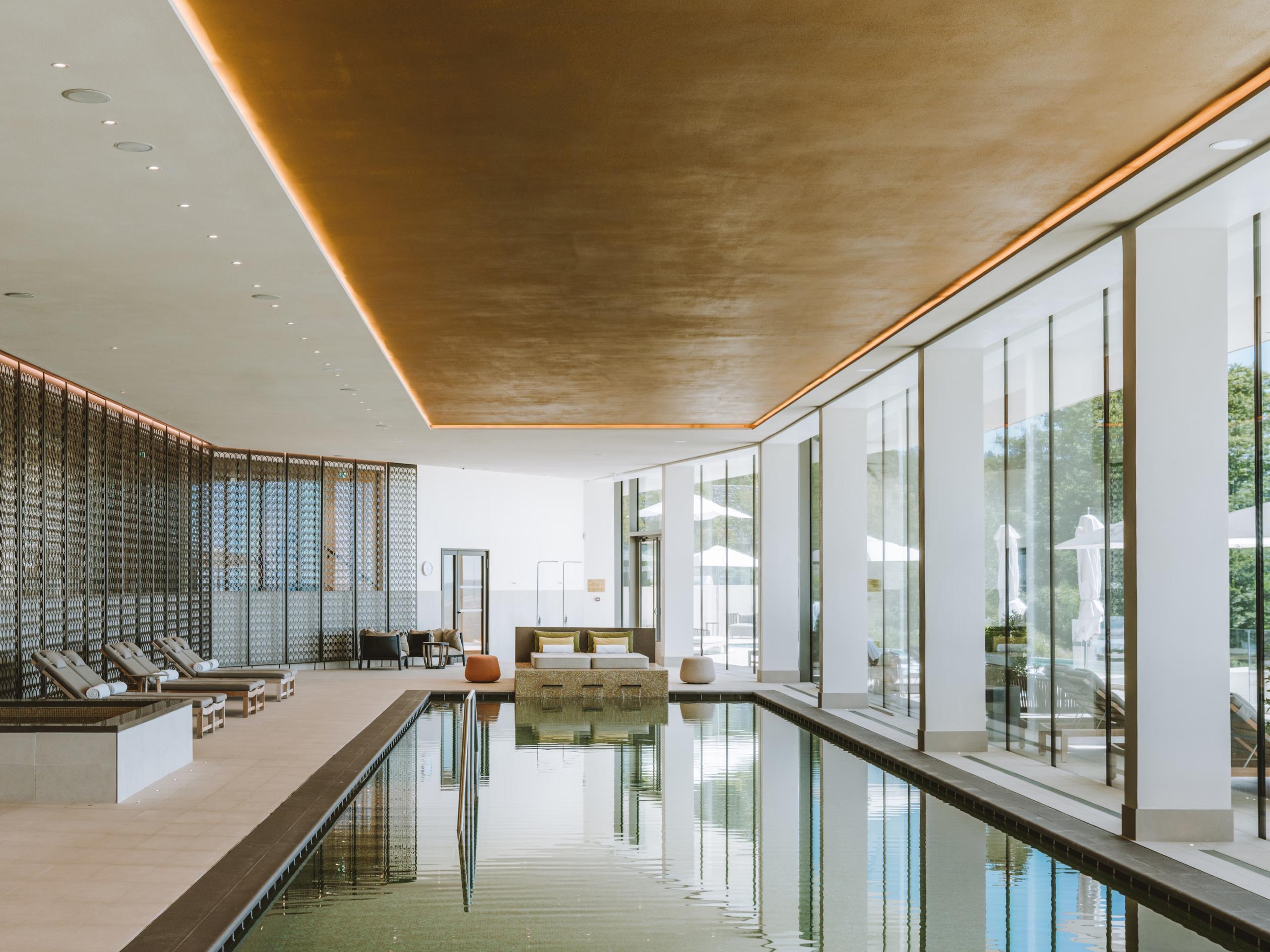 Spa with indoor pool reflecting large windows, timber walls, and natural light throughout
