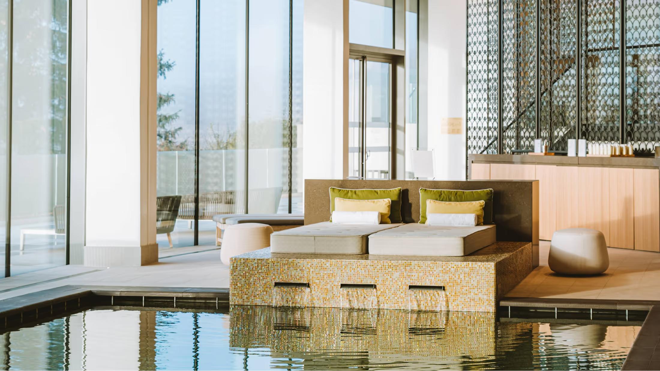 A modern spa suite with indoor pool and floor-to-ceiling windows overlooking vineyard views