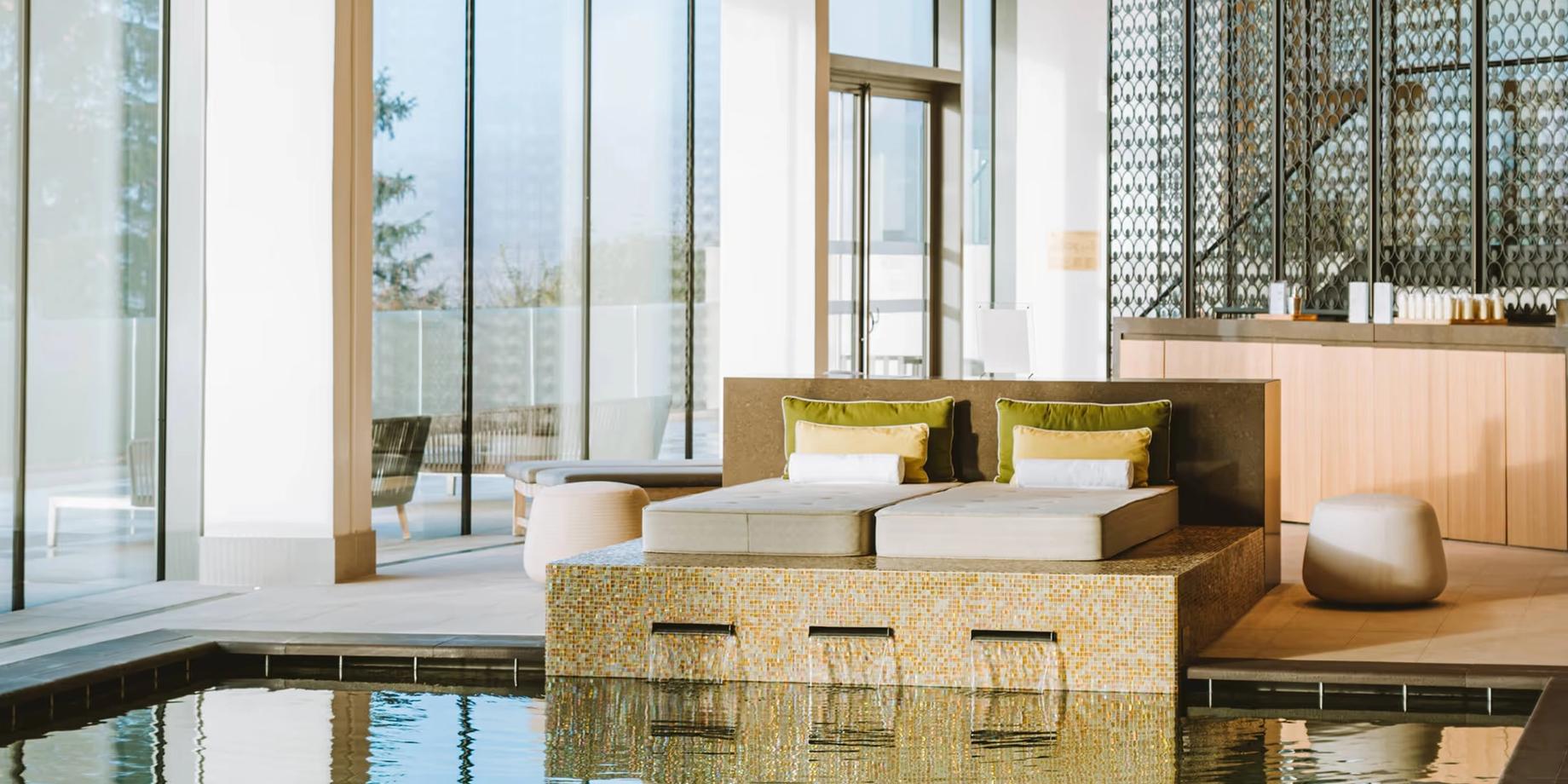 A modern spa suite with indoor pool and floor-to-ceiling windows overlooking vineyard views