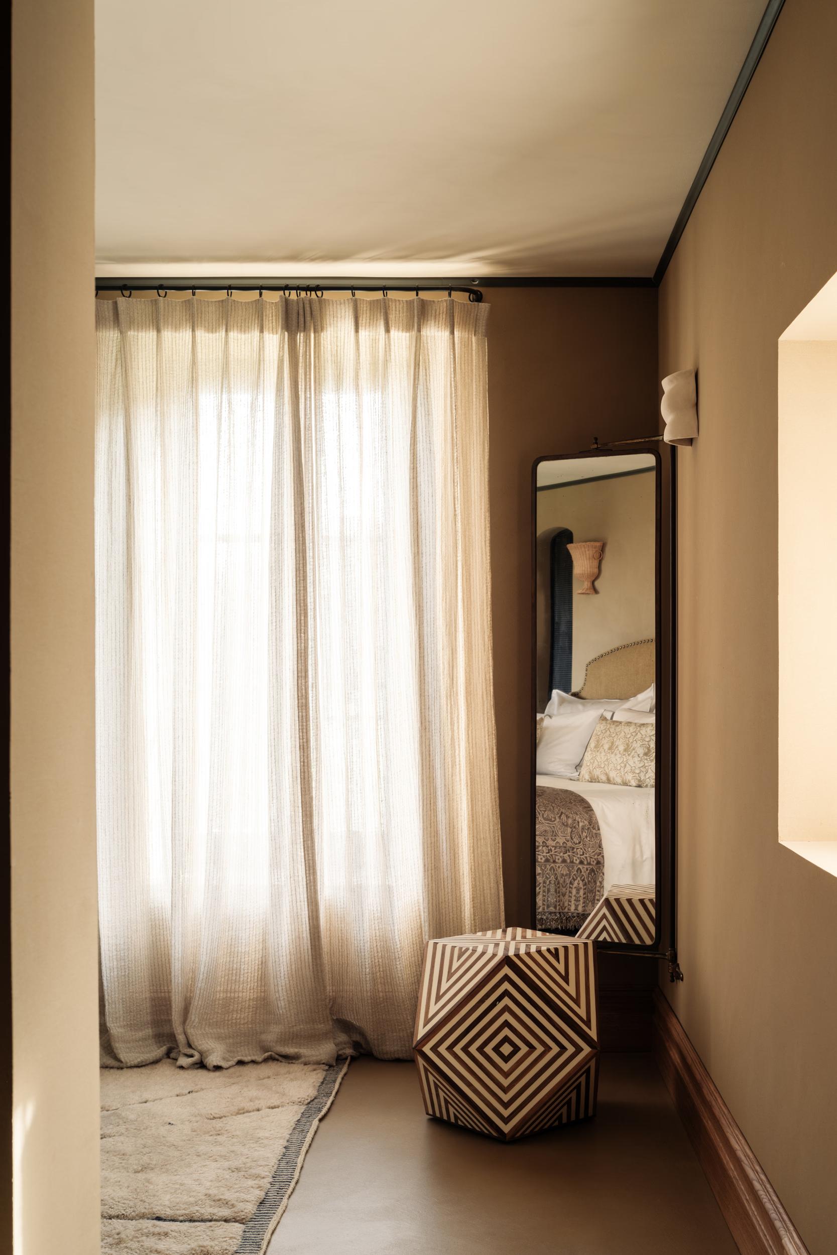La Bergerie: narrow dressing hallway with sheer linen curtains, tall mirror, geometric-woven seating bench