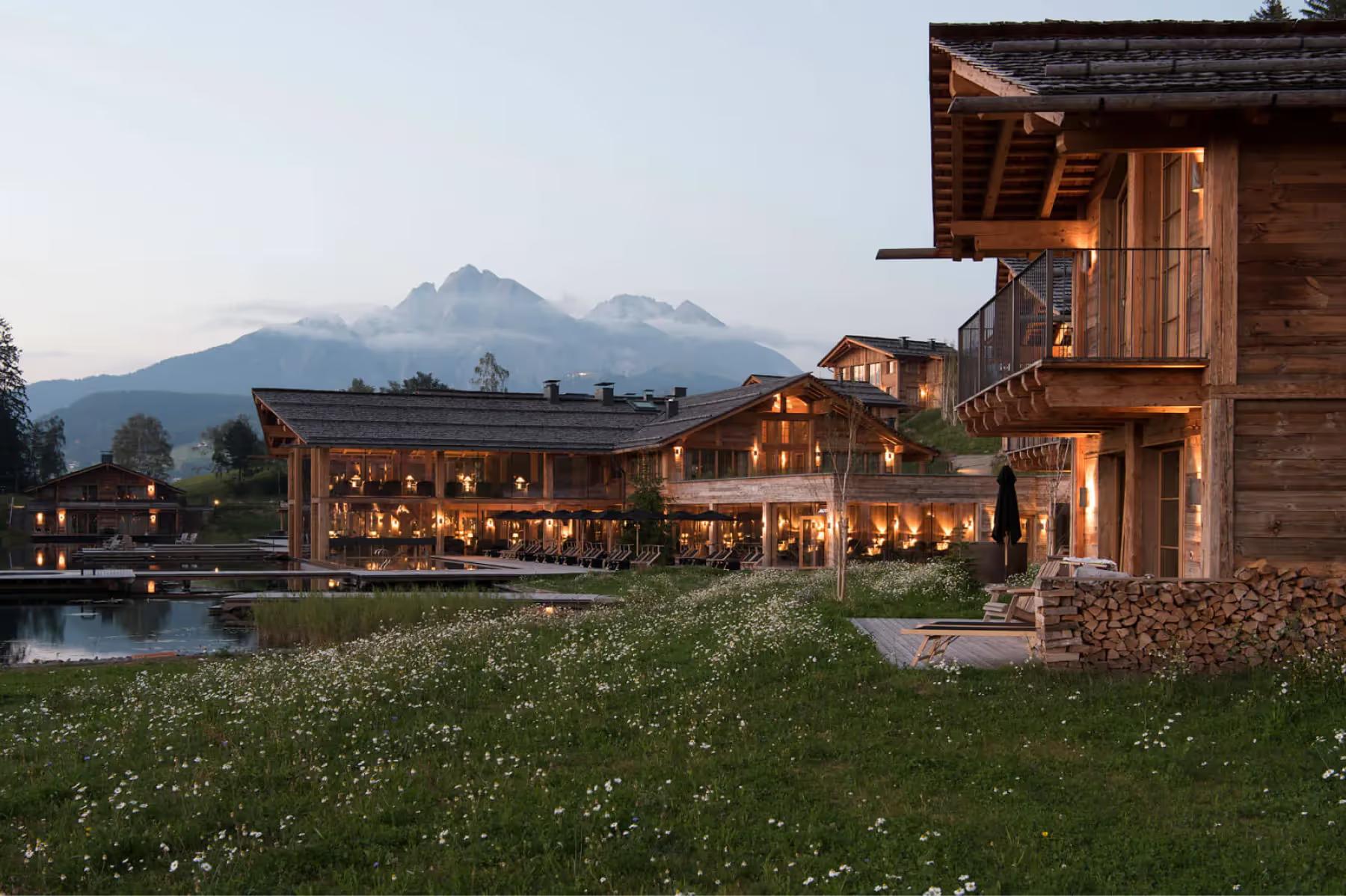 San Luis Retreat: the property at dusk with mountains rising beyond lit wooden structures