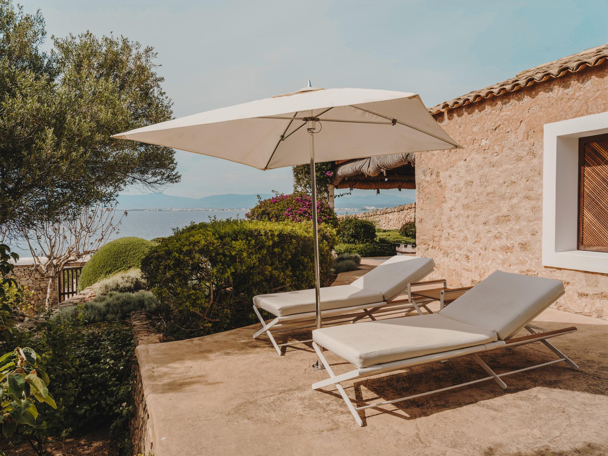 Cap Rocat: two cream lounges beneath a square parasol overlook the Bay of Palma, with magenta bougainvillea and stone walls