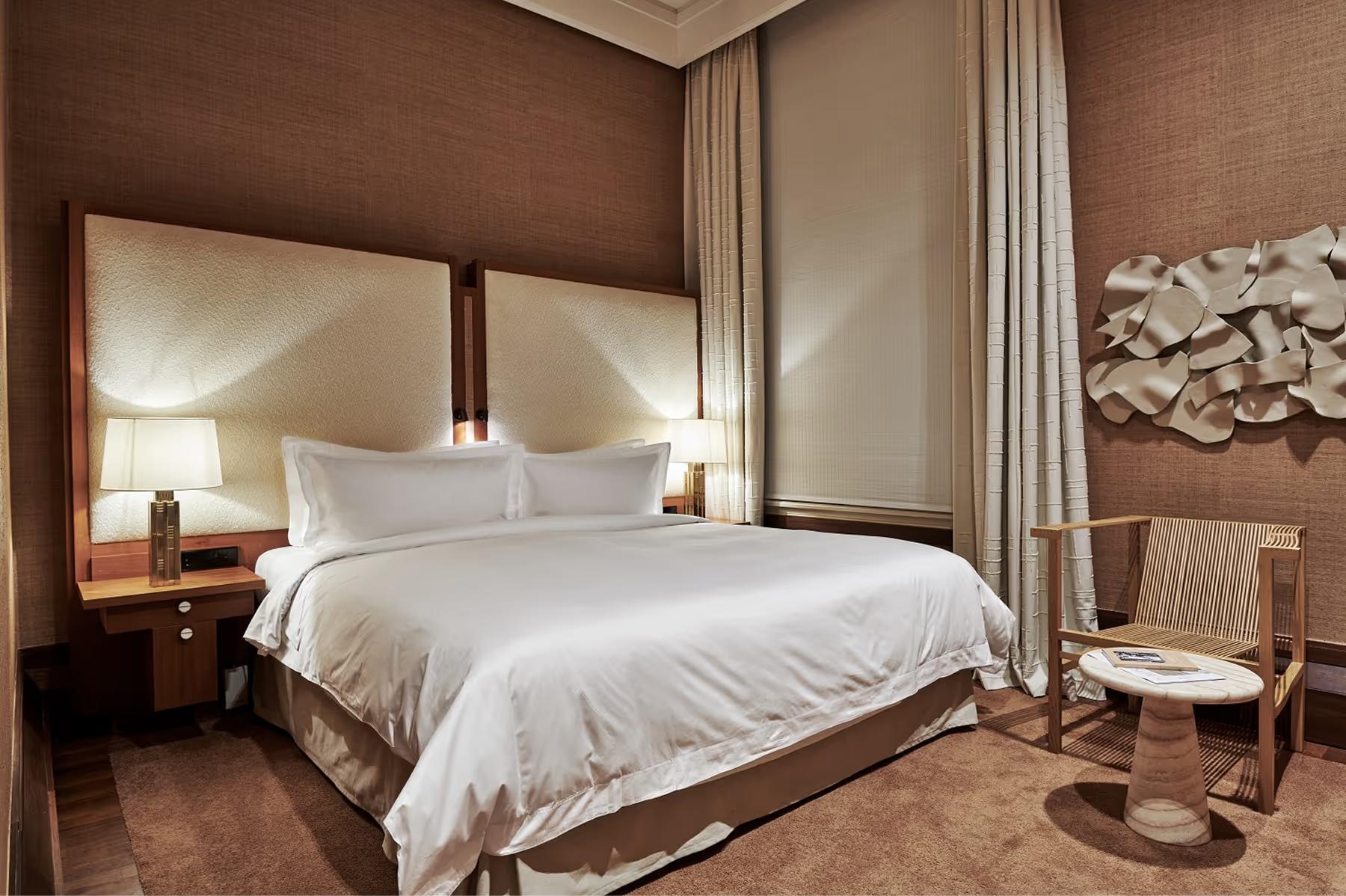 De L’Europe Amsterdam: suite bedroom with taupe upholstered walls, white bedding, and modern seating nook