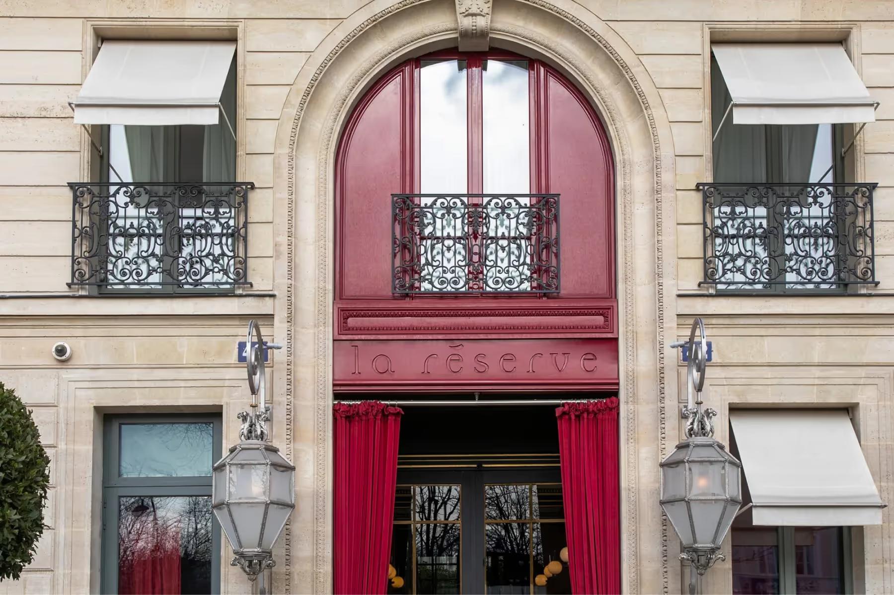 La Réserve Paris: the salmon-red arched entrance with brass lanterns on either side