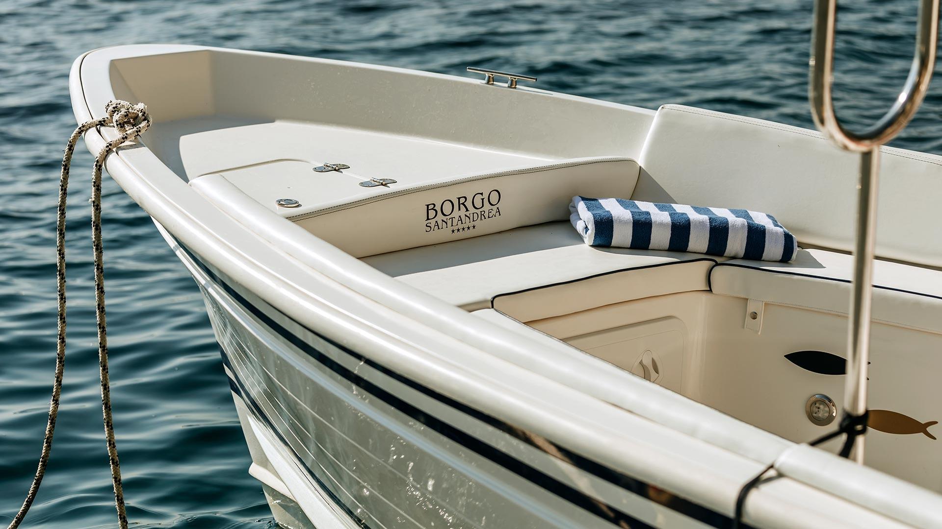 White boat moored in clear water with striped cushions and rope detail