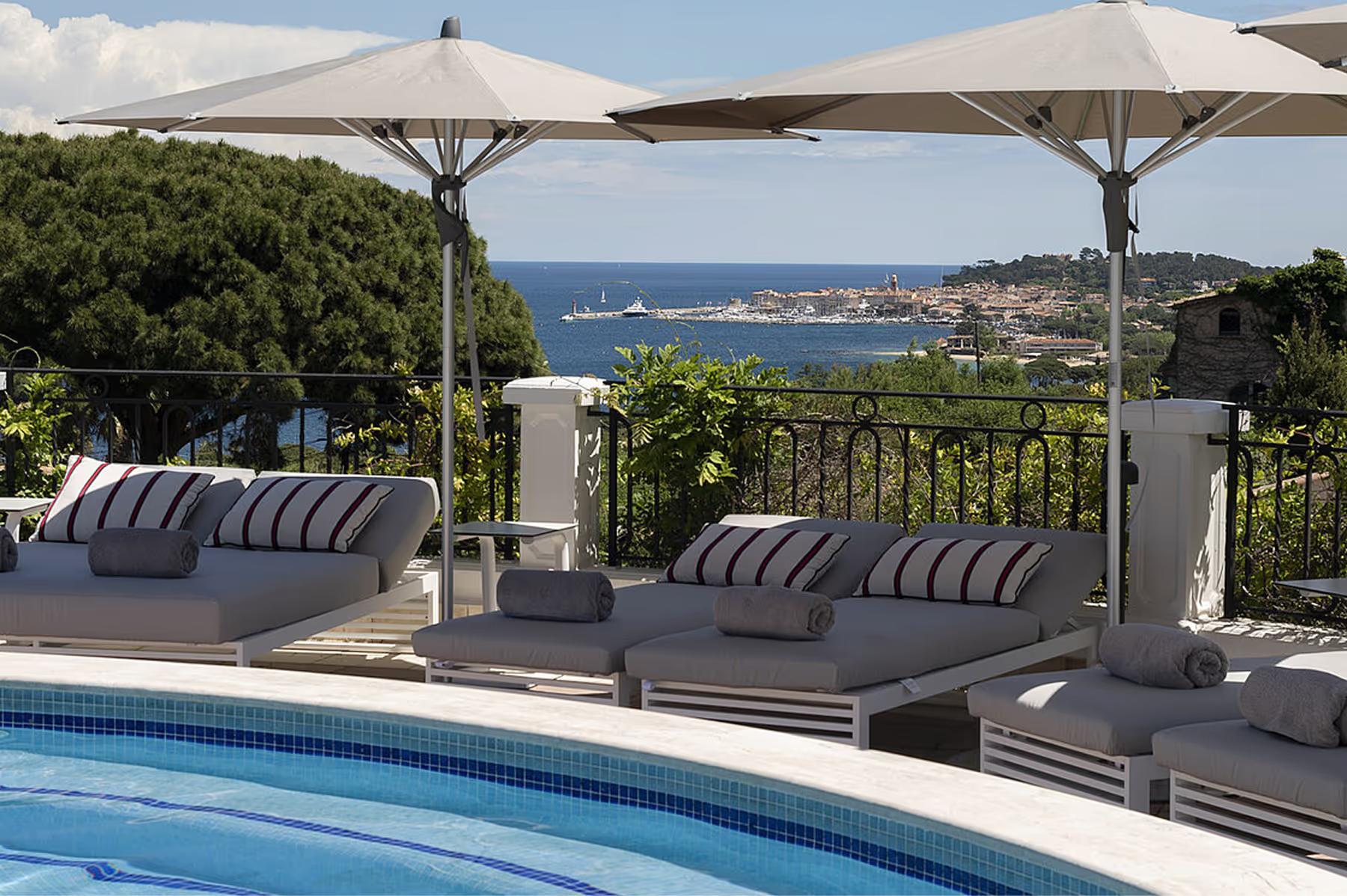 Shaded lounge terrace with striped cushions overlooking the bay