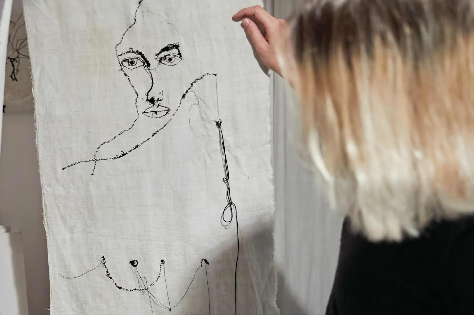 La Residencia: artist sketching on linen fabric, creating linear portrait drawing with pen