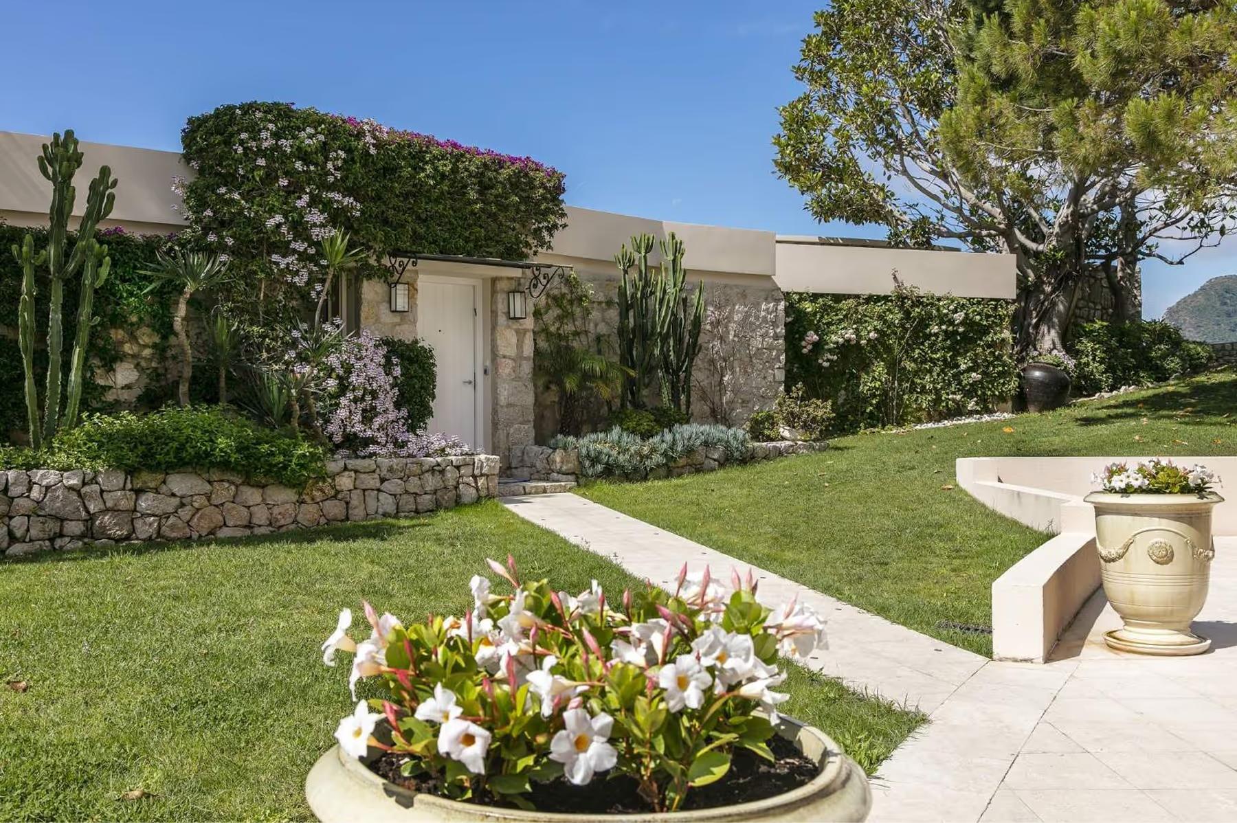 Hotel Cap-Estel: white stone pathways and colorful flower beds outside residential villas