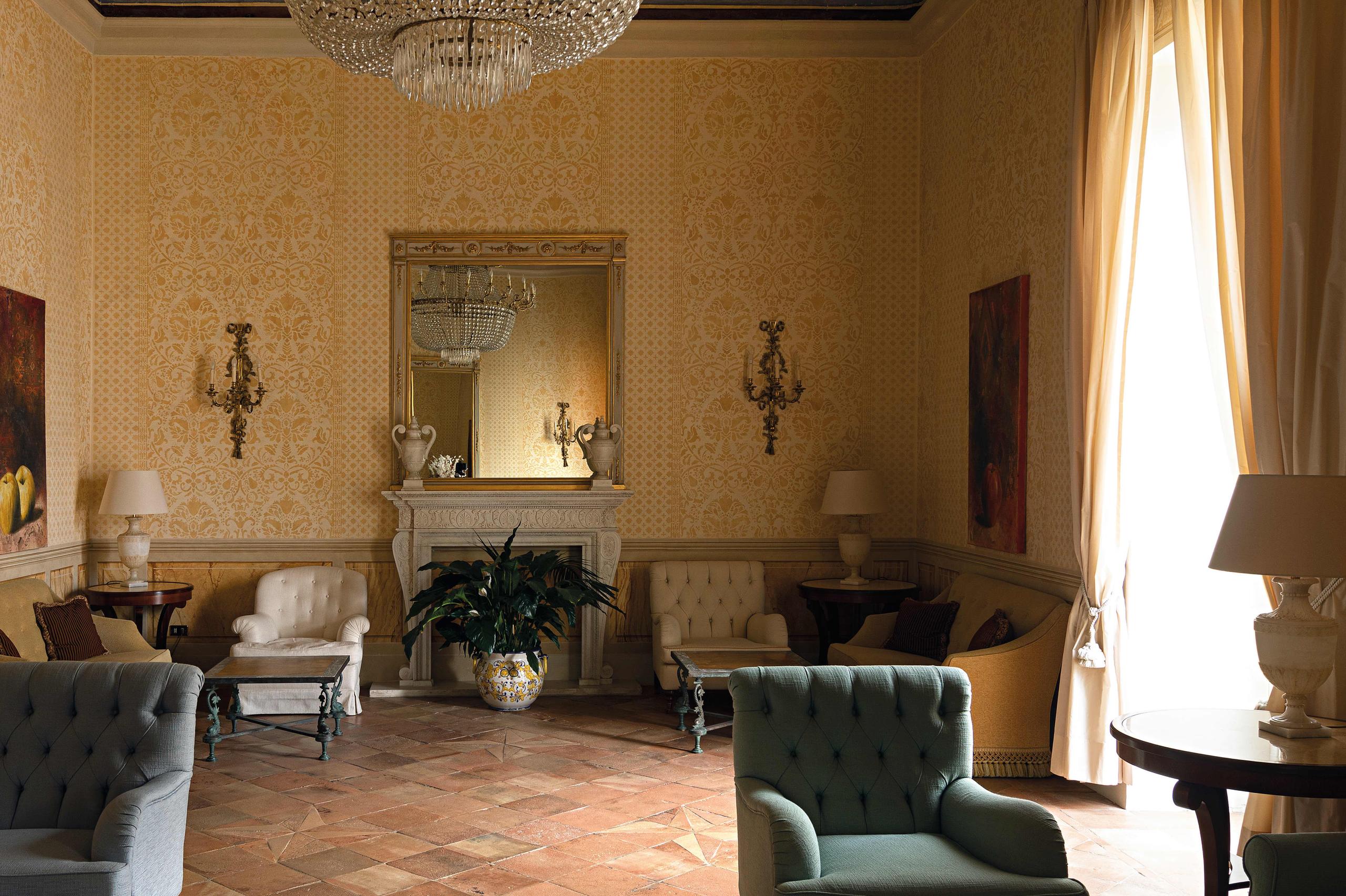 Caruso: arched interior with fireplace, golden walls, ornate fixture, mirrors, and lounge seating