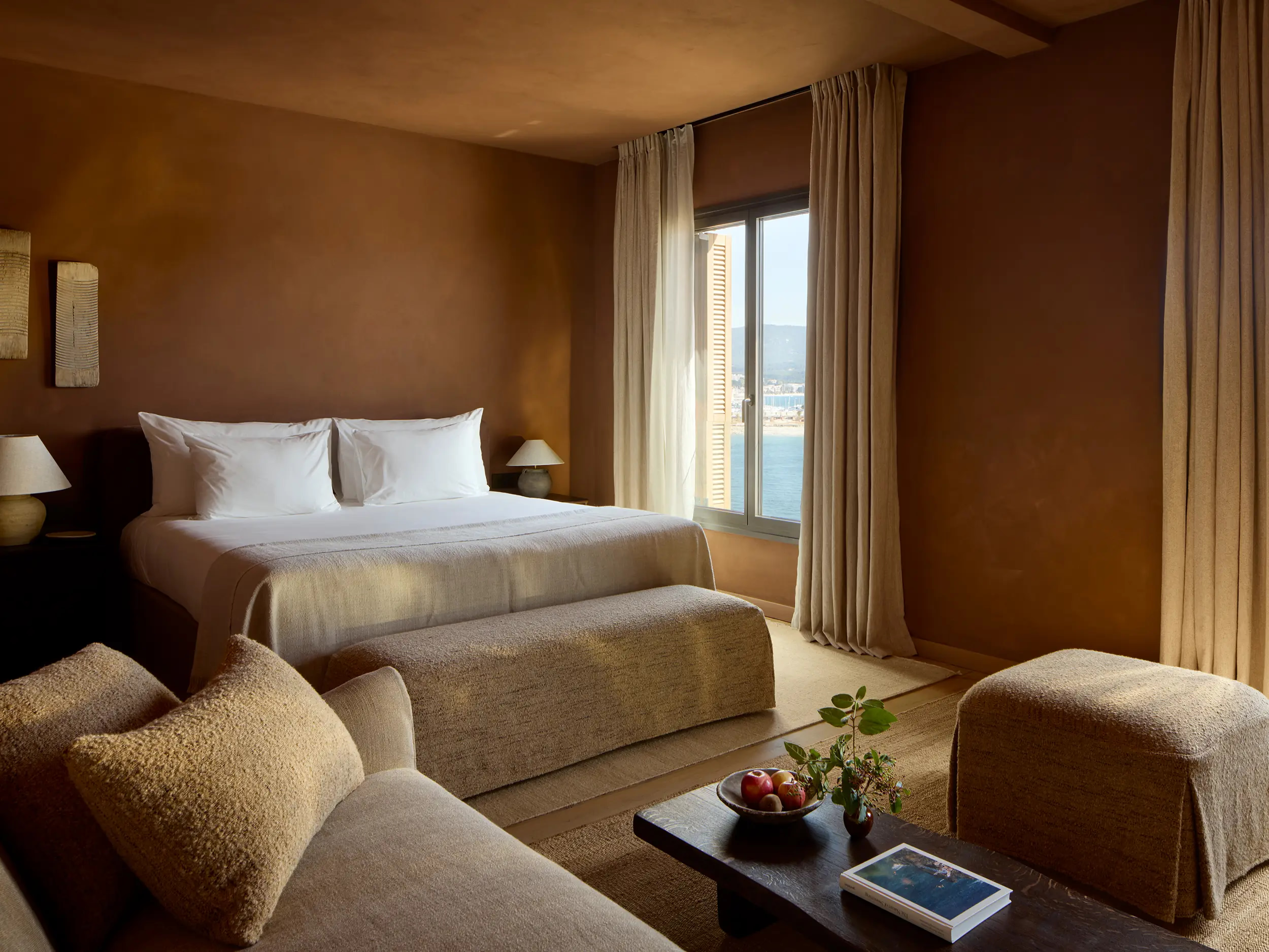 Zannier Île de Bendor: a corner suite bed faces floor to ceiling windows over the harbor and distant hills