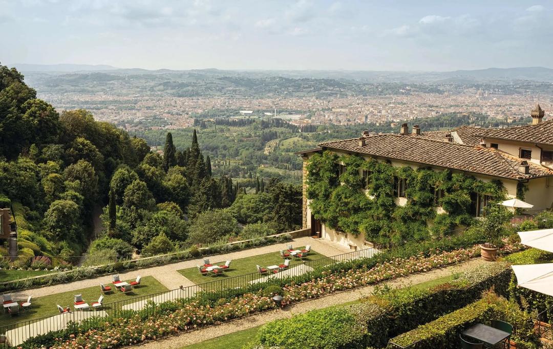 The wisteria-covered wing of Villa San Michele above a rose garden, with Florence spread across the valley below