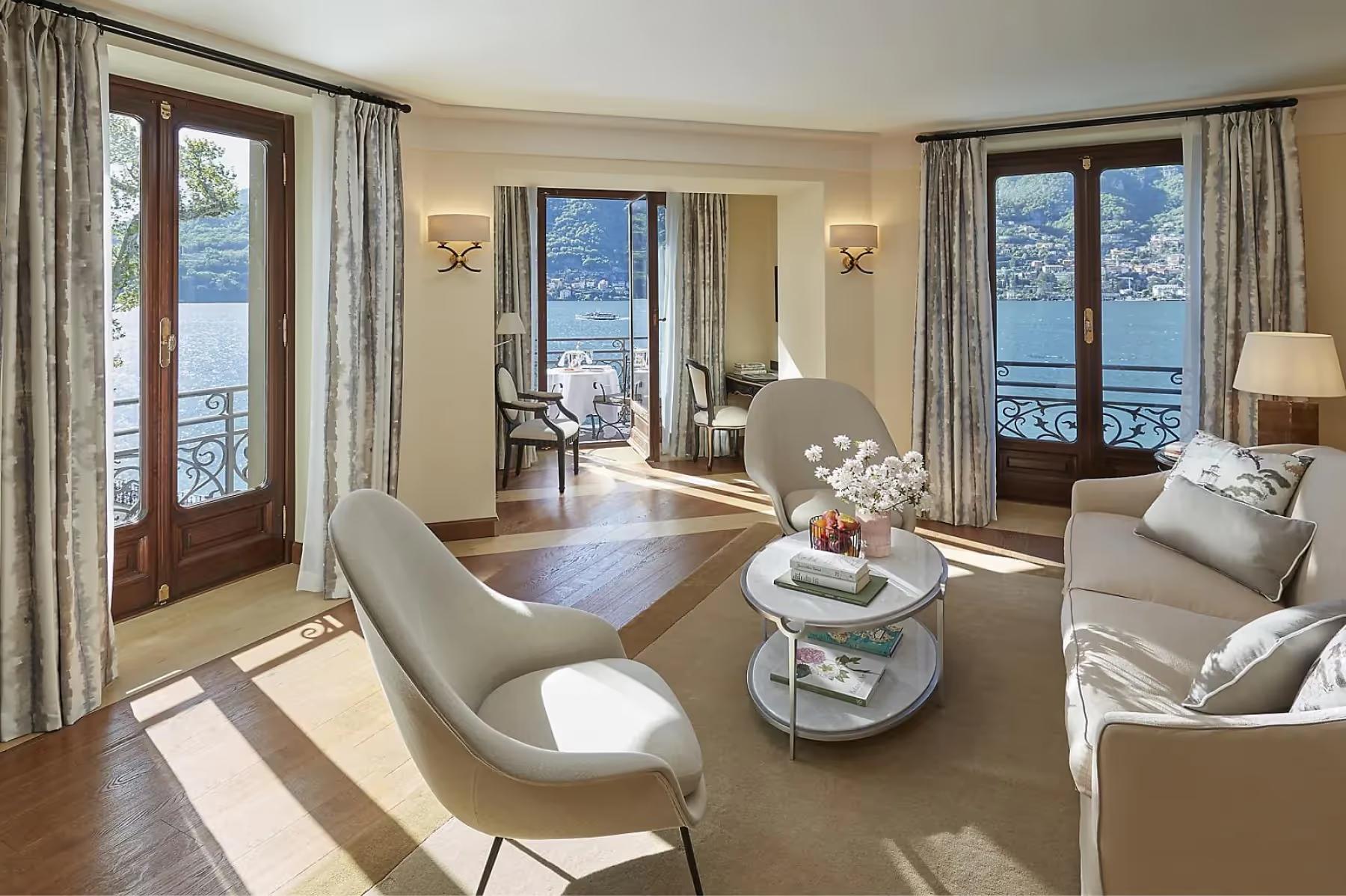 Contemporary suite with cream furnishings, glass doors opening to lake views and mountains