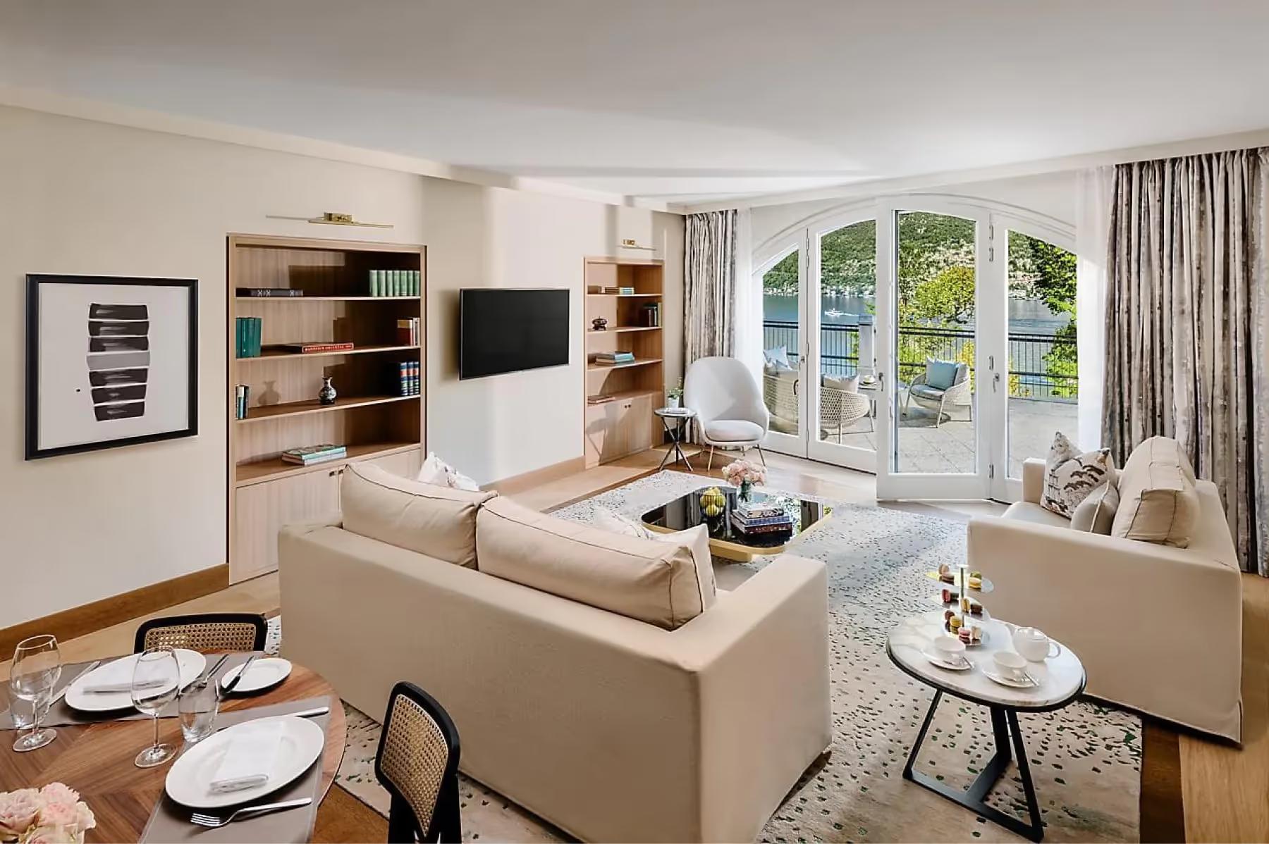 Mandarin Oriental, Lake Como: living room with cream sofa facing lake views through glass doors and built-in shelving