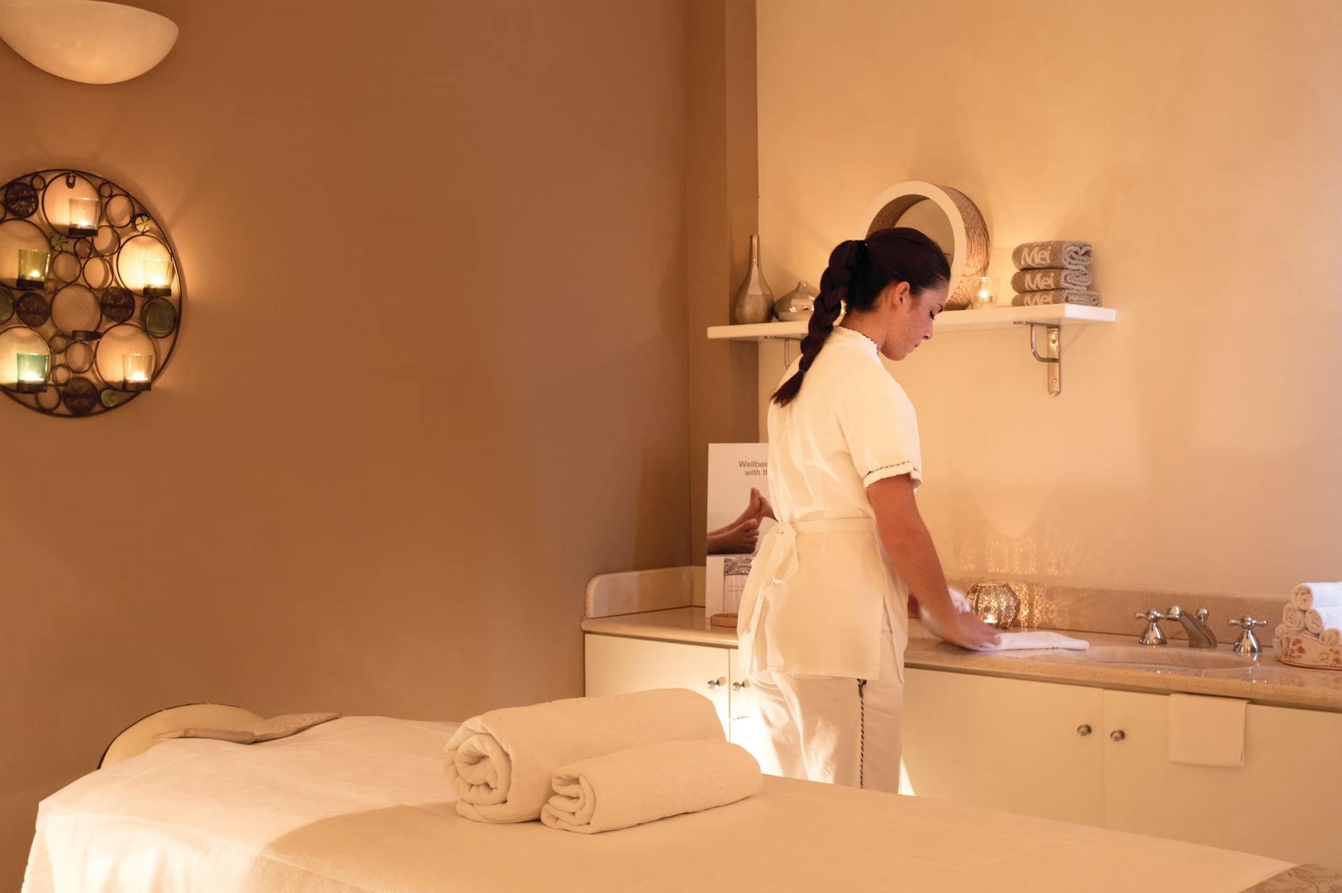 A spa therapist preparing for a treatment in a light-filled wellness space