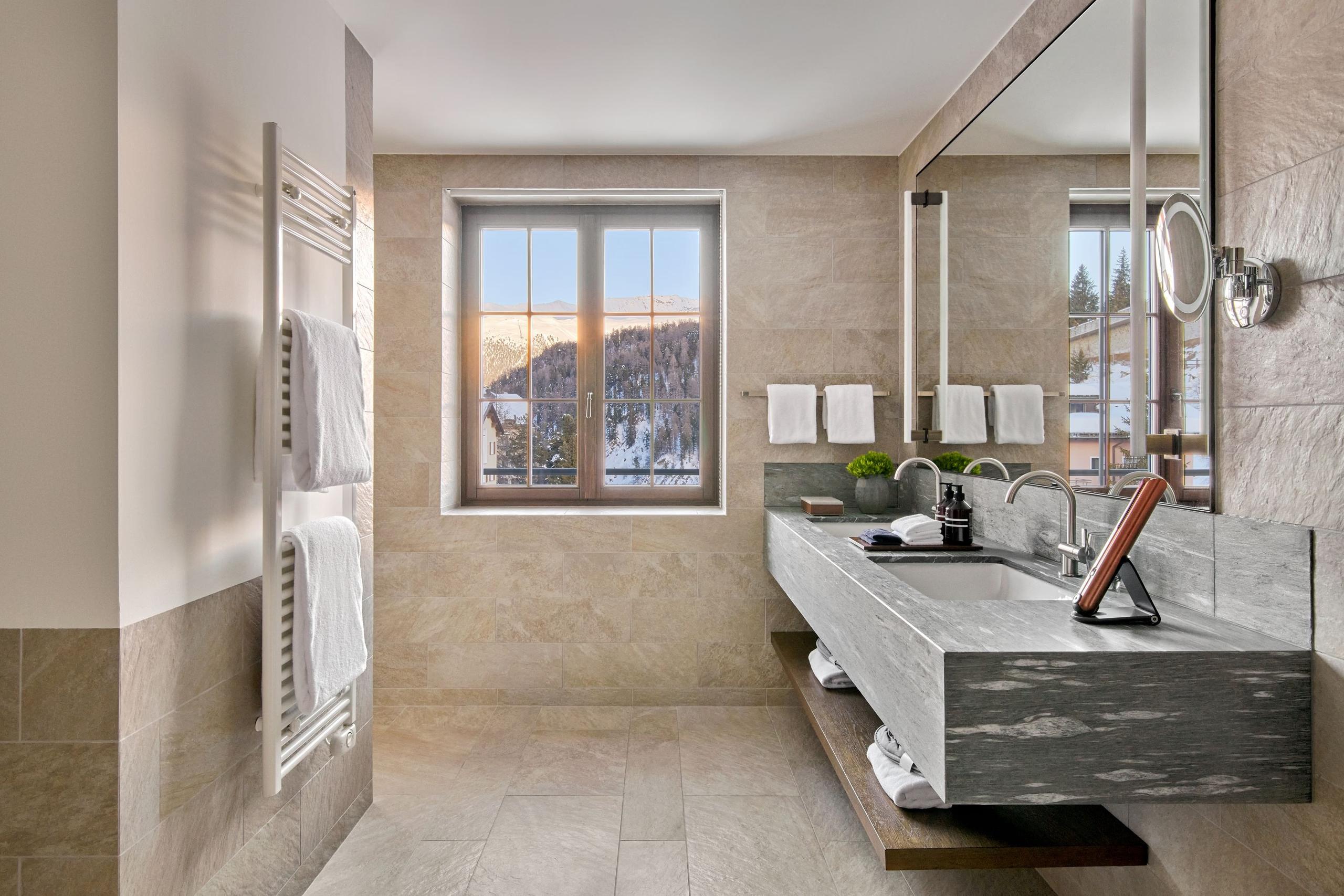 Marble bathroom with stone walls, open showers, and windows overlooking mountains