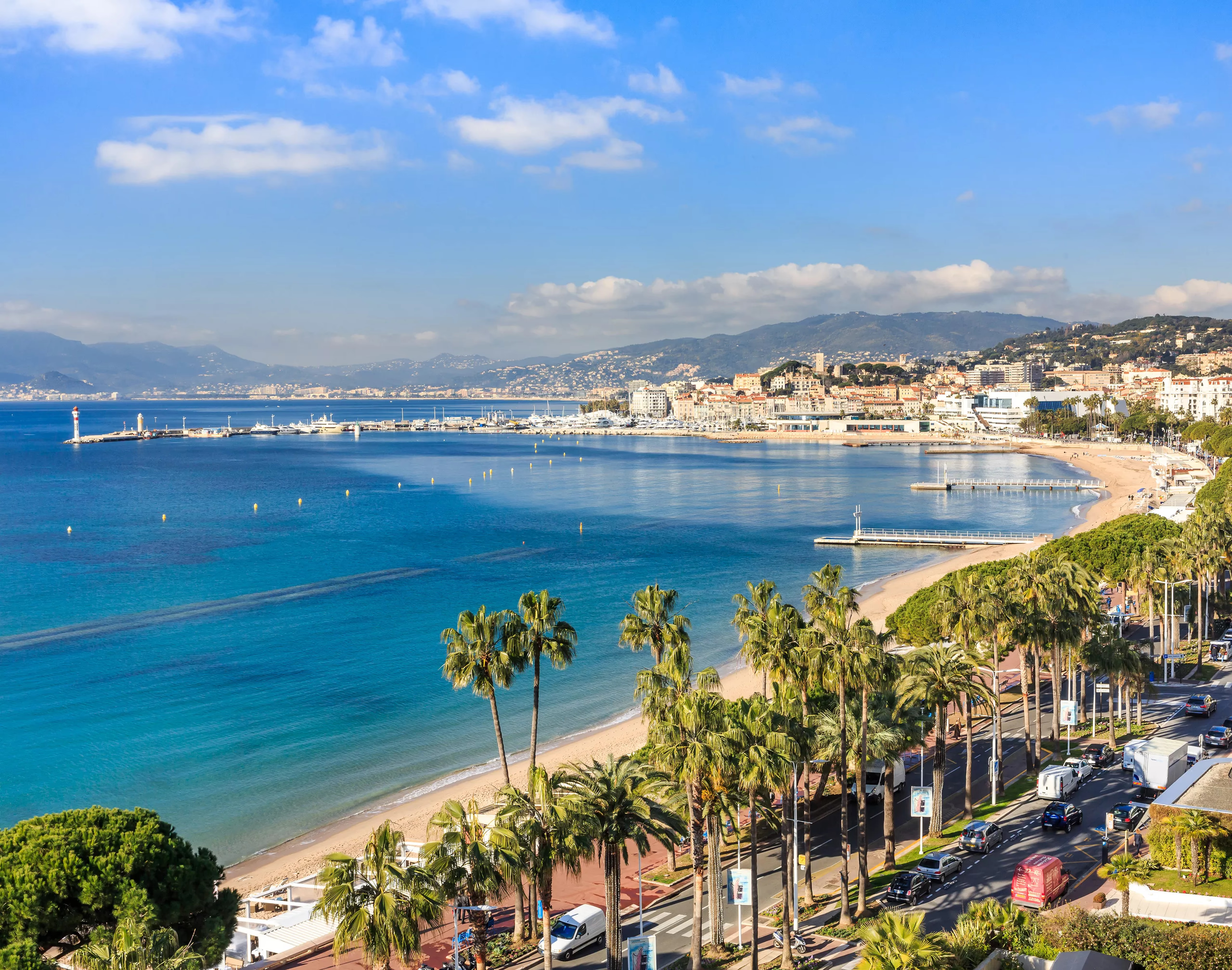 Carlton Cannes: coastal view of Cannes with blue waters, palm-lined Boulevard de la Croisette, and white sandy beaches