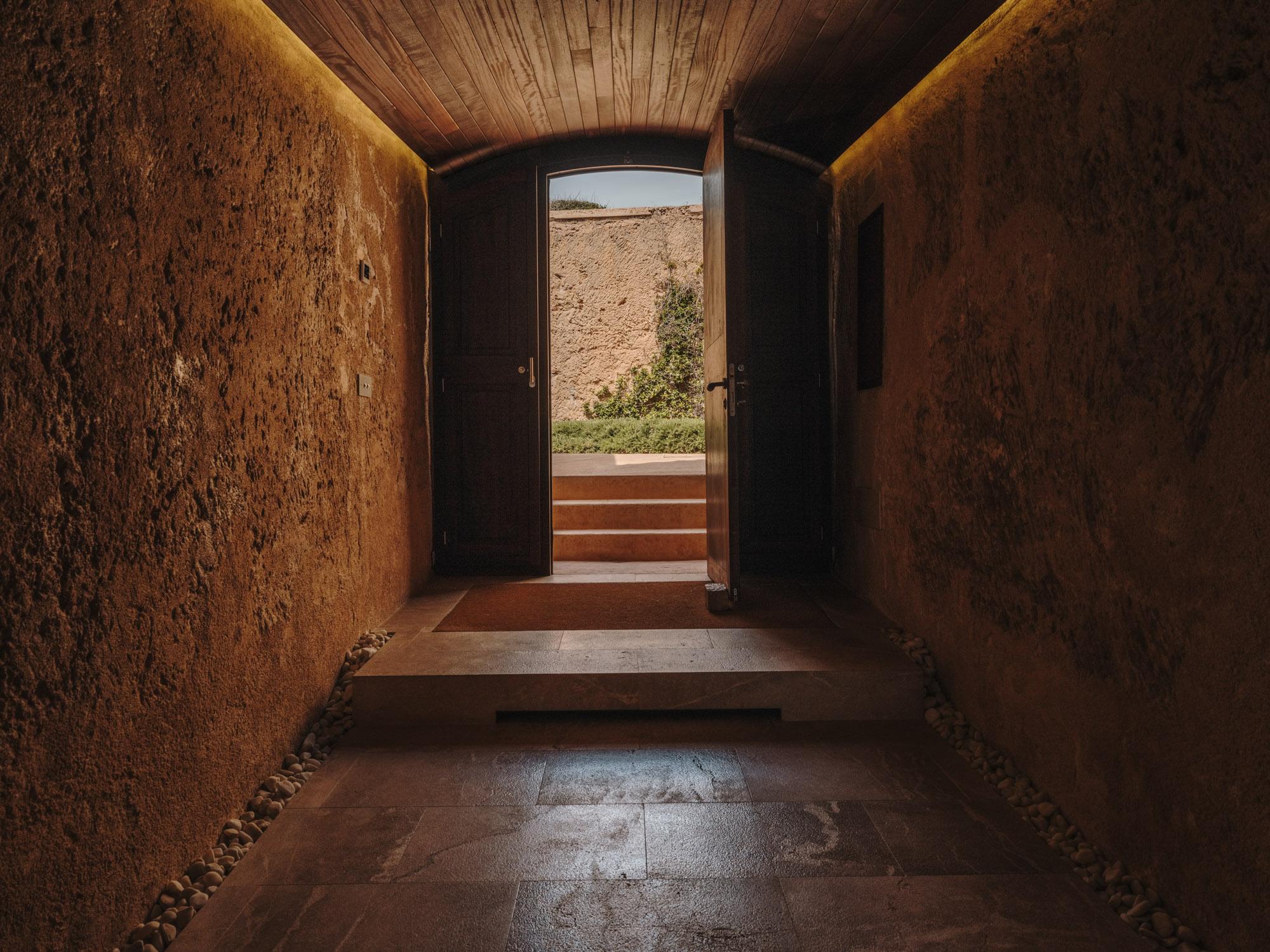 Cap Rocat: a dark stone corridor frames coastal light and vegetation beyond, in fortress architecture
