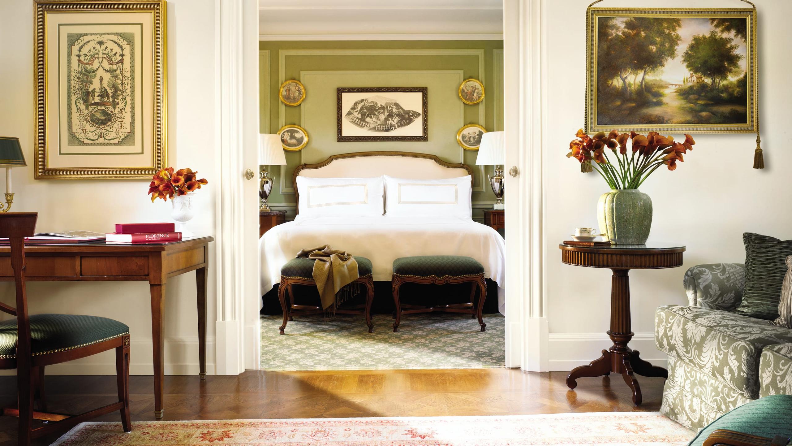 A guest suite with cream-colored walls, an ornate fireplace, and framed artworks