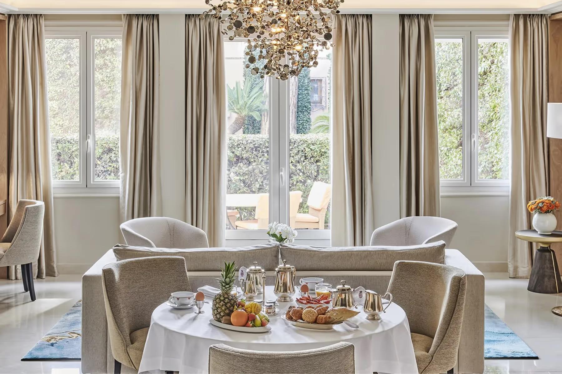 Interior lounge with round table, large windows, and garden vistas