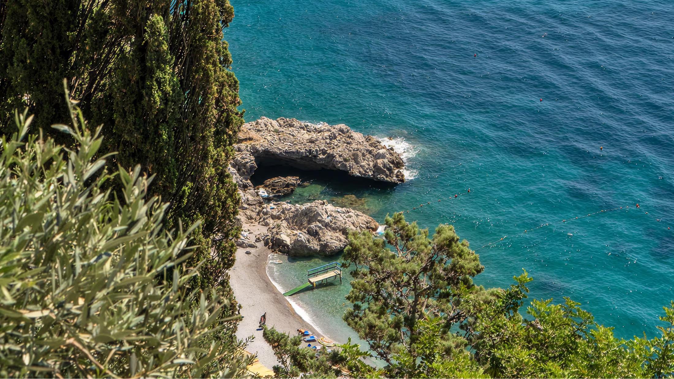 Emerald cove below terraced gardens and cypress trees on the Amalfi Coast