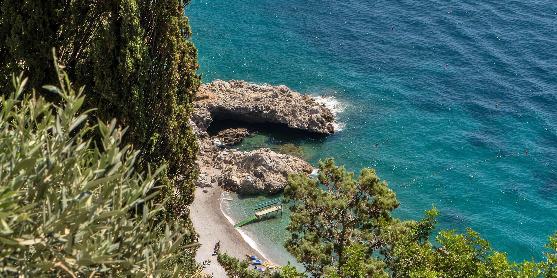 Emerald cove below terraced gardens and cypress trees on the Amalfi Coast