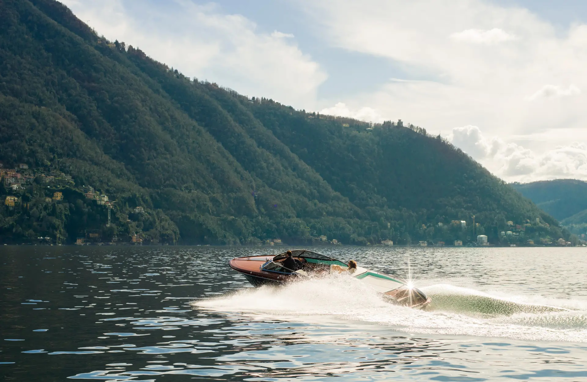 A person paddleboarding on blue lake water with forested mountains in background