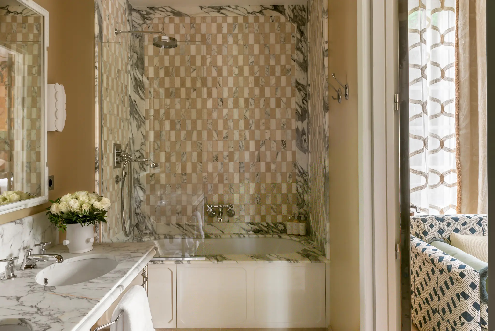 Bathroom with white marble vanity, patterned tile shower enclosure, and brass fixtures