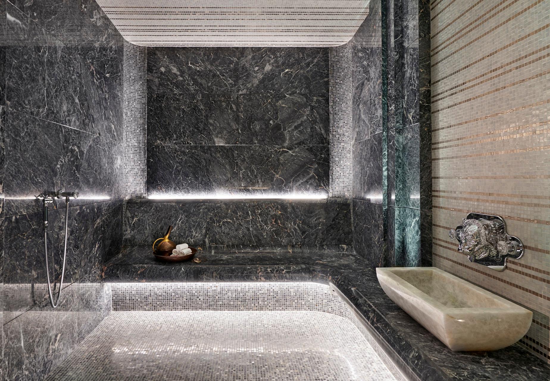 Four Seasons Hotel George V: a spa bathroom with dark marble walls, a deep soaking tub, and natural light