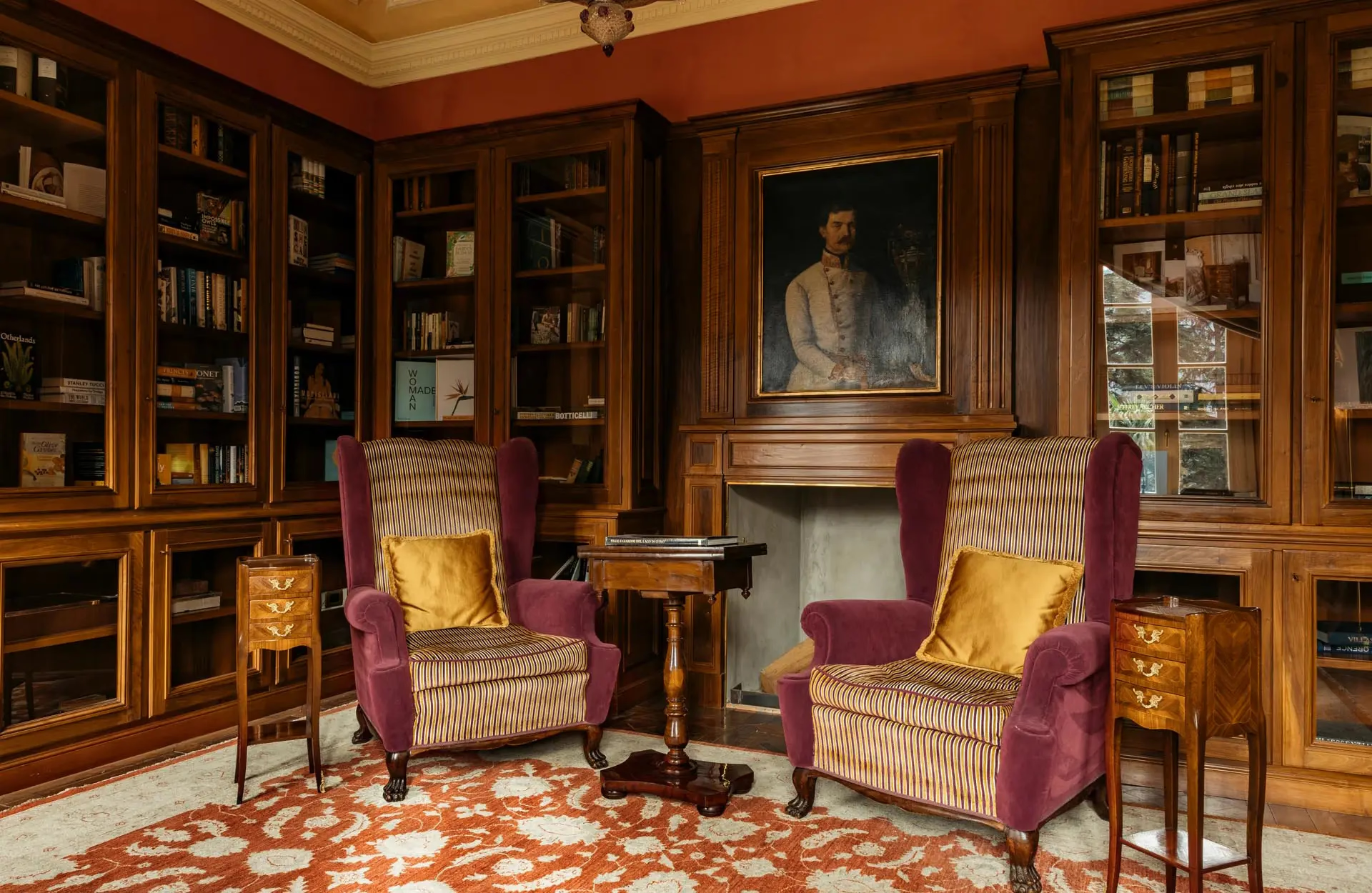 A library with burgundy cabinetry, fireplace, purple velvet seating, and wood paneling
