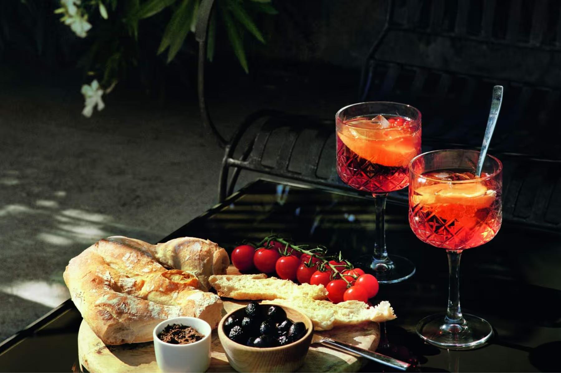 Le Mas de Chabran: aperitif with fresh bread, olives, and red wine on outdoor table with greenery backdrop
