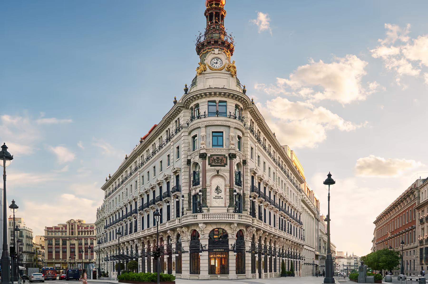 Ornate 19th-century building facade with clock tower and arched windows on a Madrid street corner