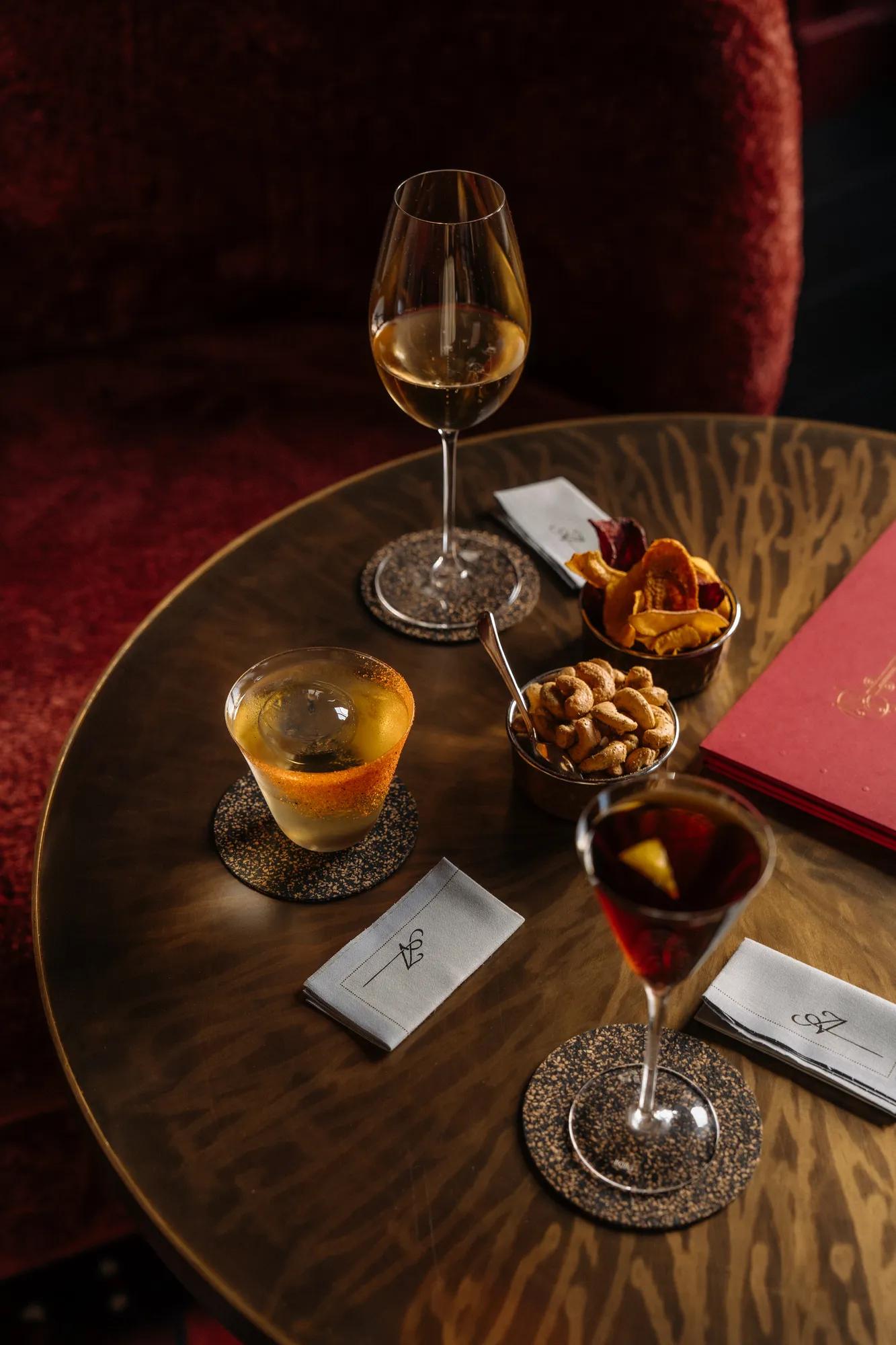 Rosewood Amsterdam: cocktails and bar snacks on a round wooden table at Advocatuur