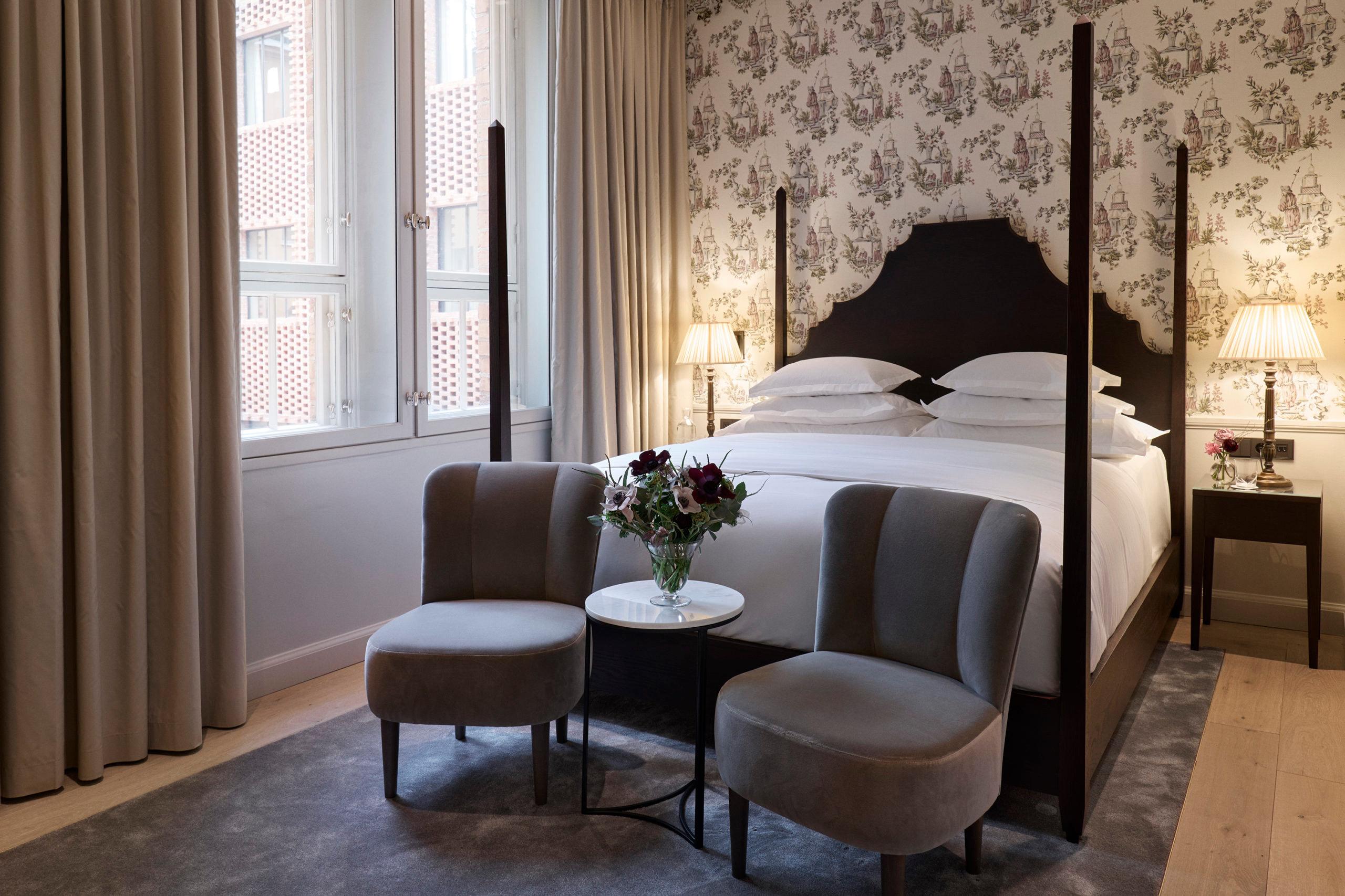 Suite with patterned wallpaper, four-poster bed, and lounge seating area