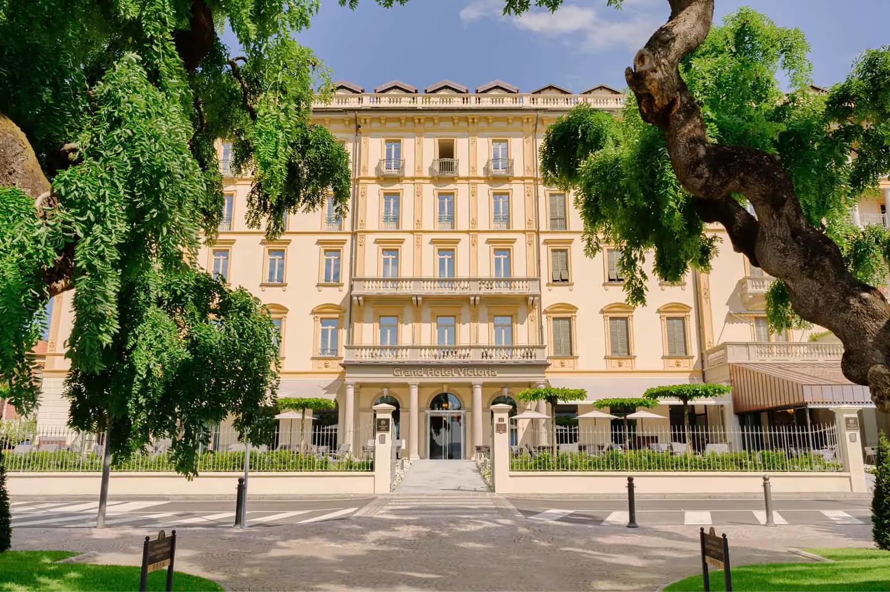 Grand Hotel Victoria Concept & Spa: the hotel’s cream and gold facade with a formal plaza and small trees in front