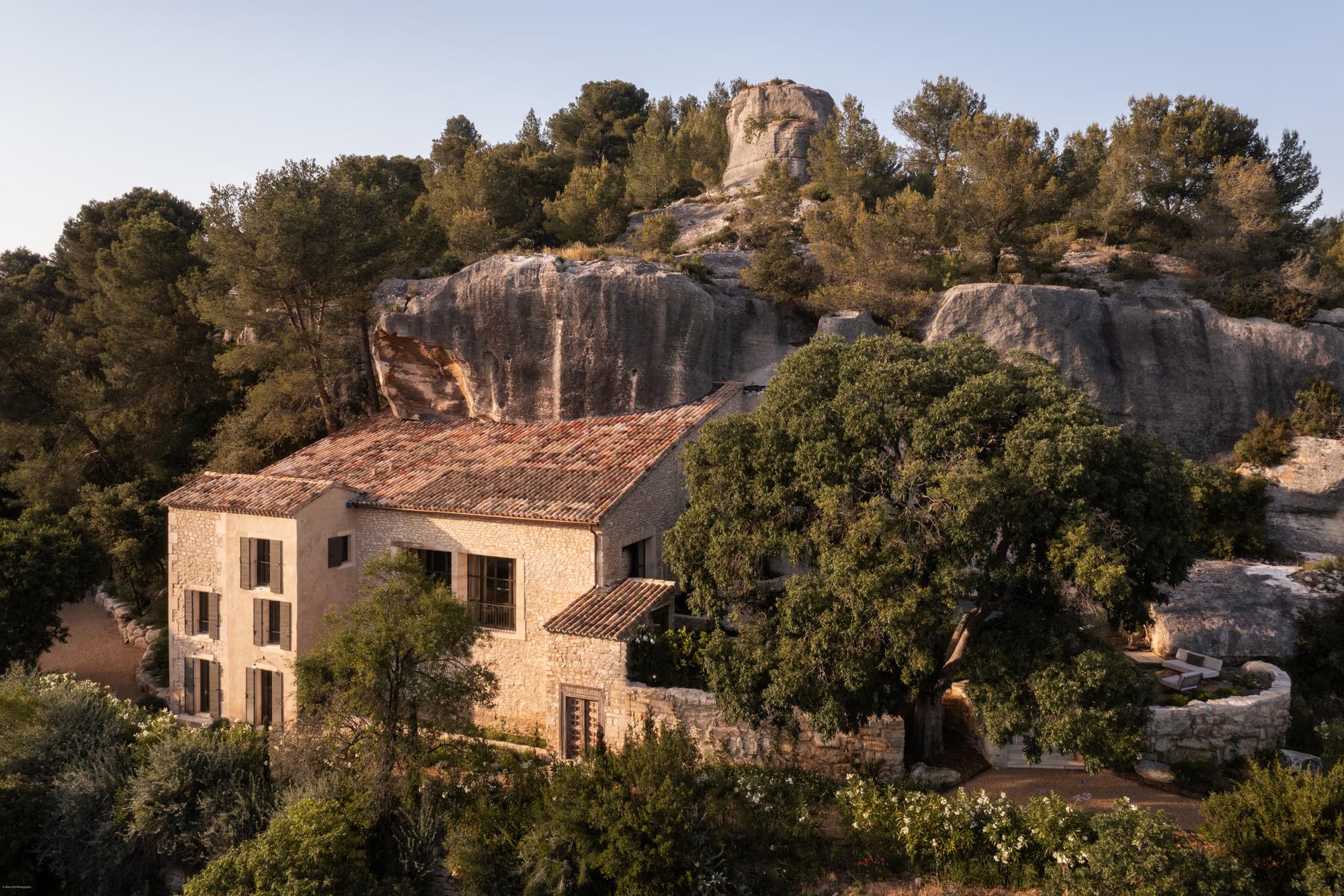 Stone villa with clay-tile roof set among conifers and limestone cliffs