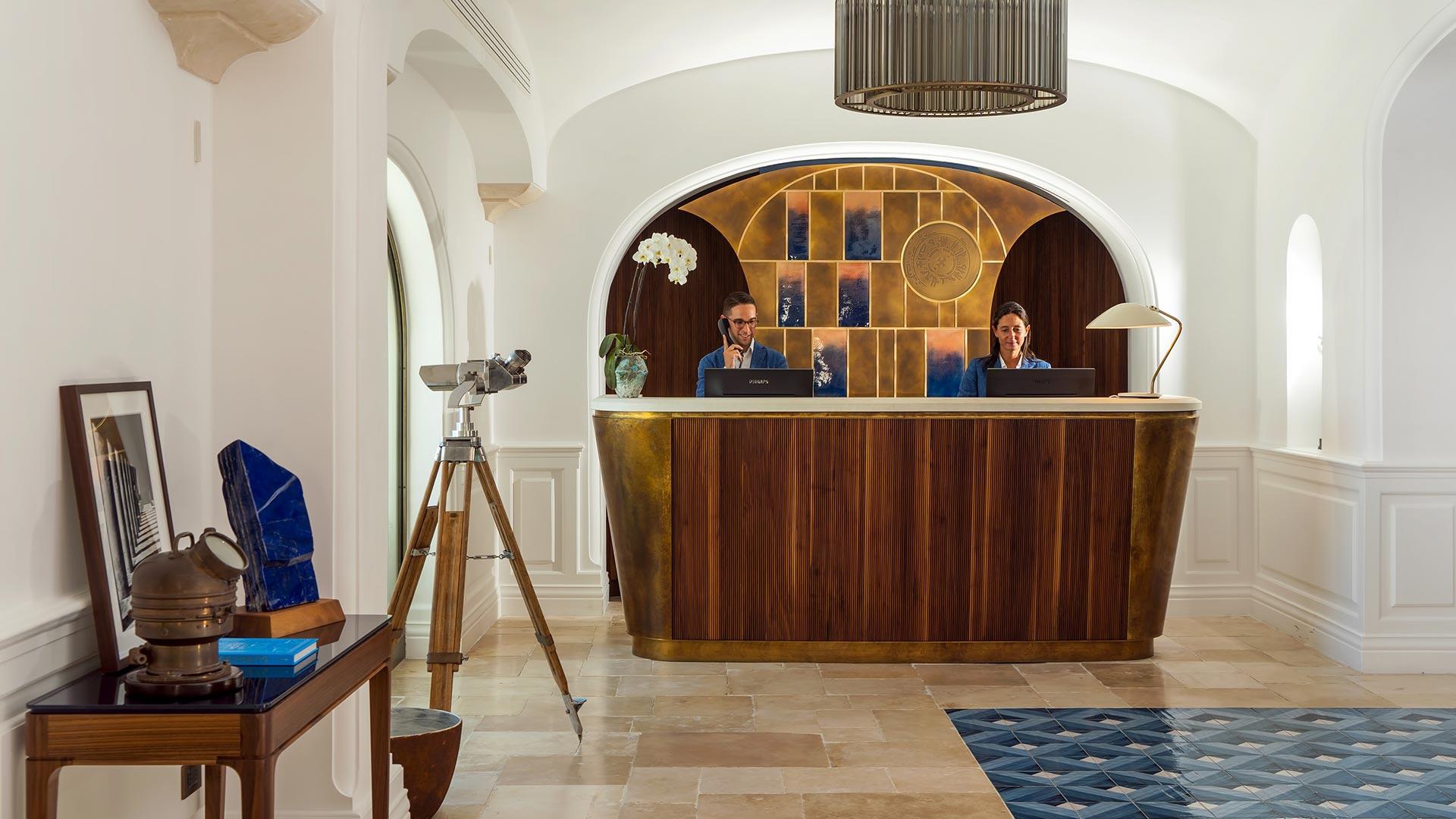 Reception desk in curved stone alcove with wooden cabinetry in whitewashed interior