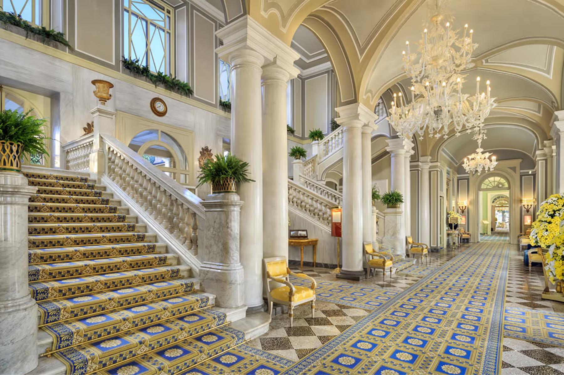 Grand marble staircase with sweeping balustrades in a columned neoclassical hallway